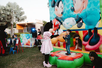Minnie mouse greets a child on a bouncy castle.