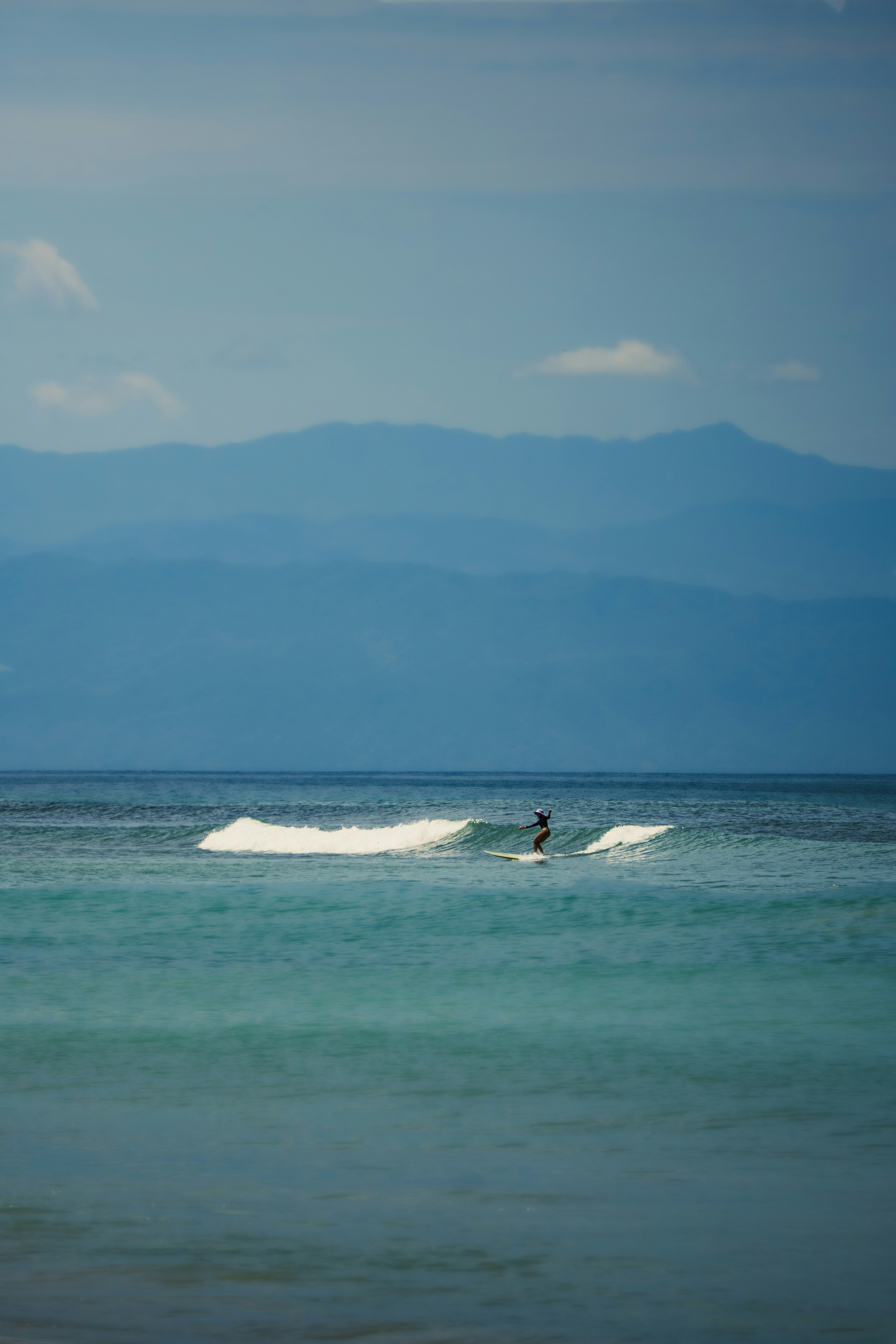 Surfer riding a wave with mountains in background