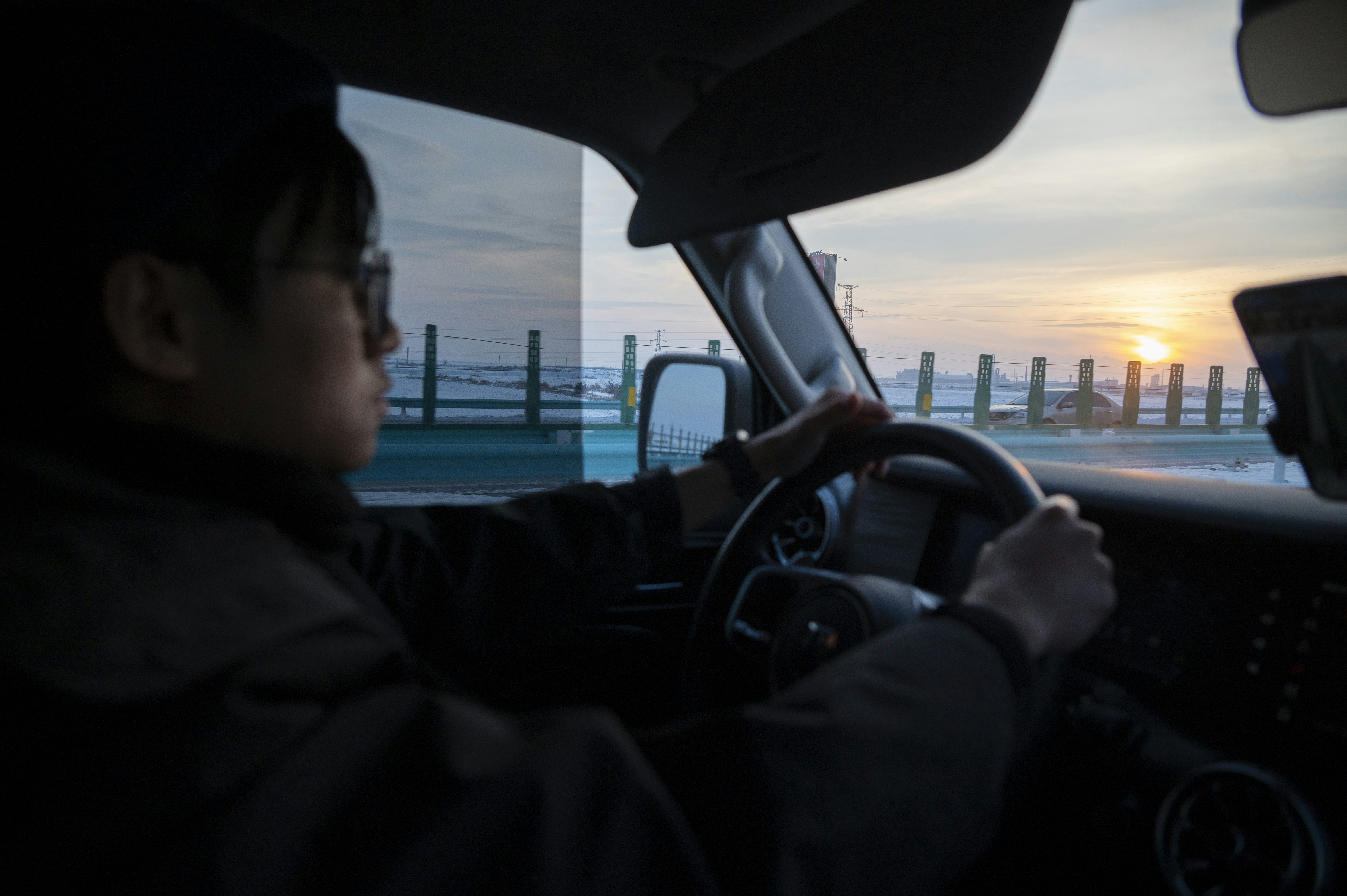 Person driving a car towards the sunset