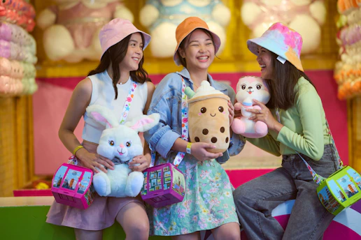 Three friends holding plush toys and smiling