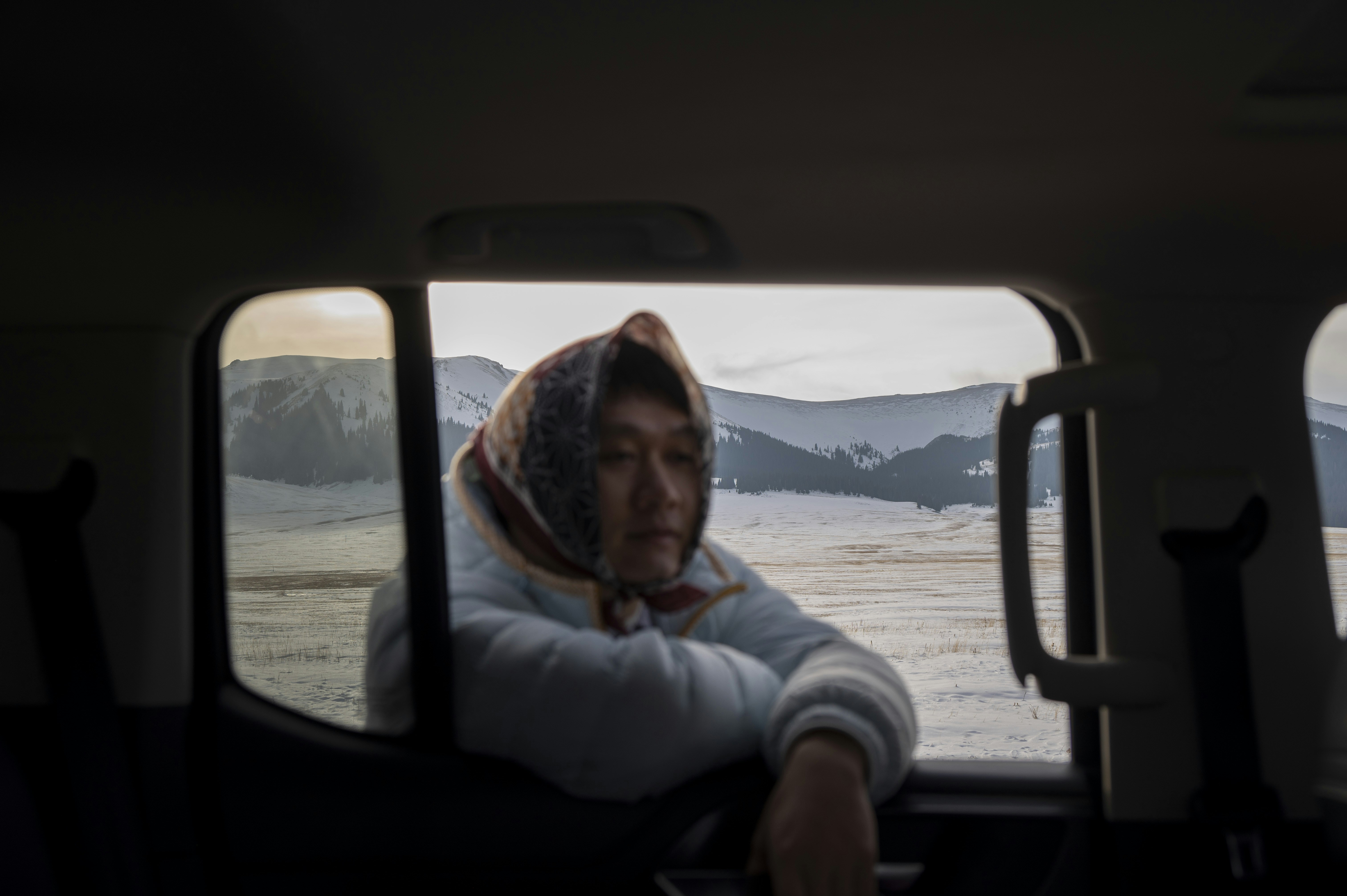 Woman looking out car window at snowy landscape