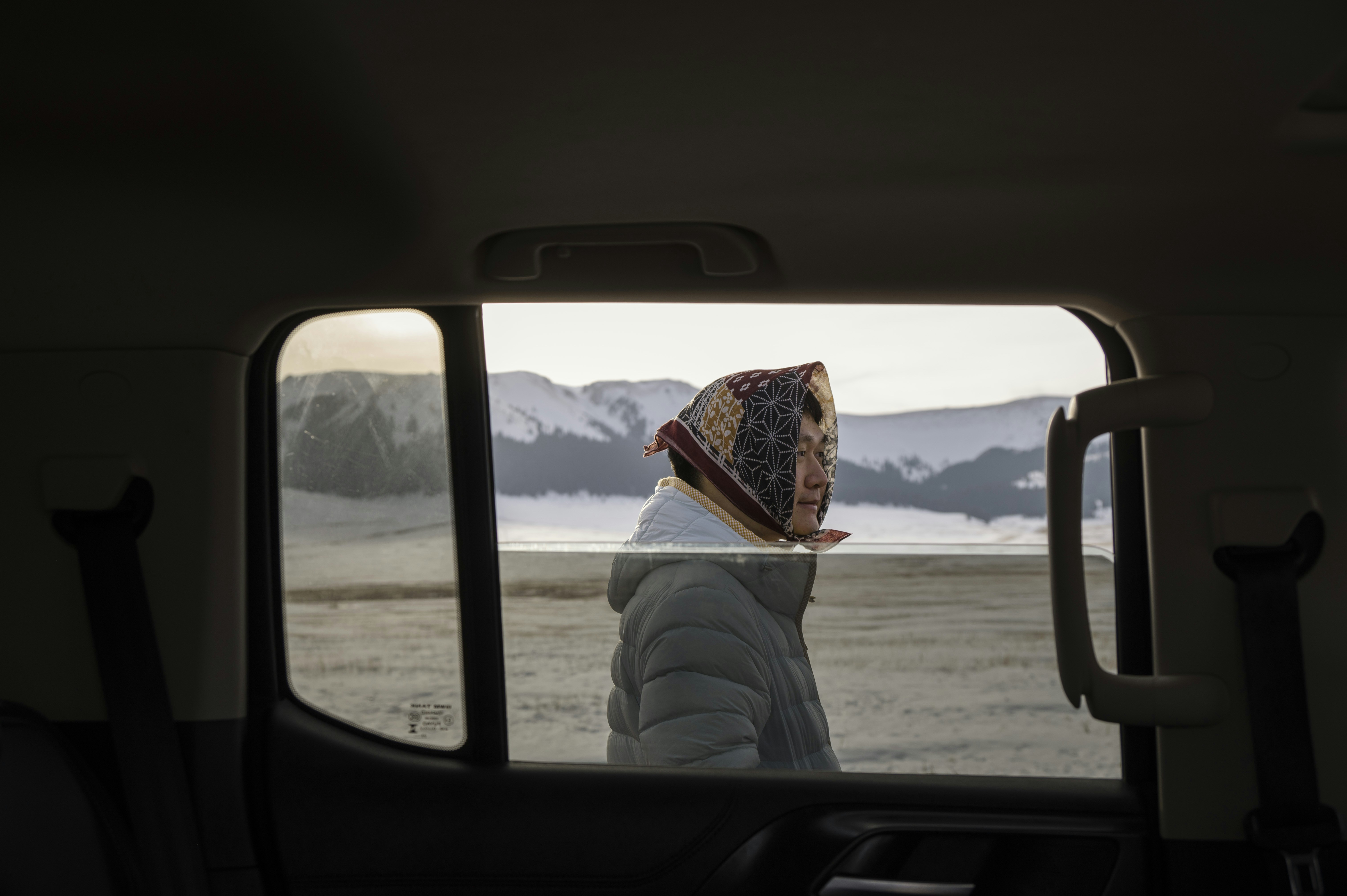 Person looking out car window at snowy mountains