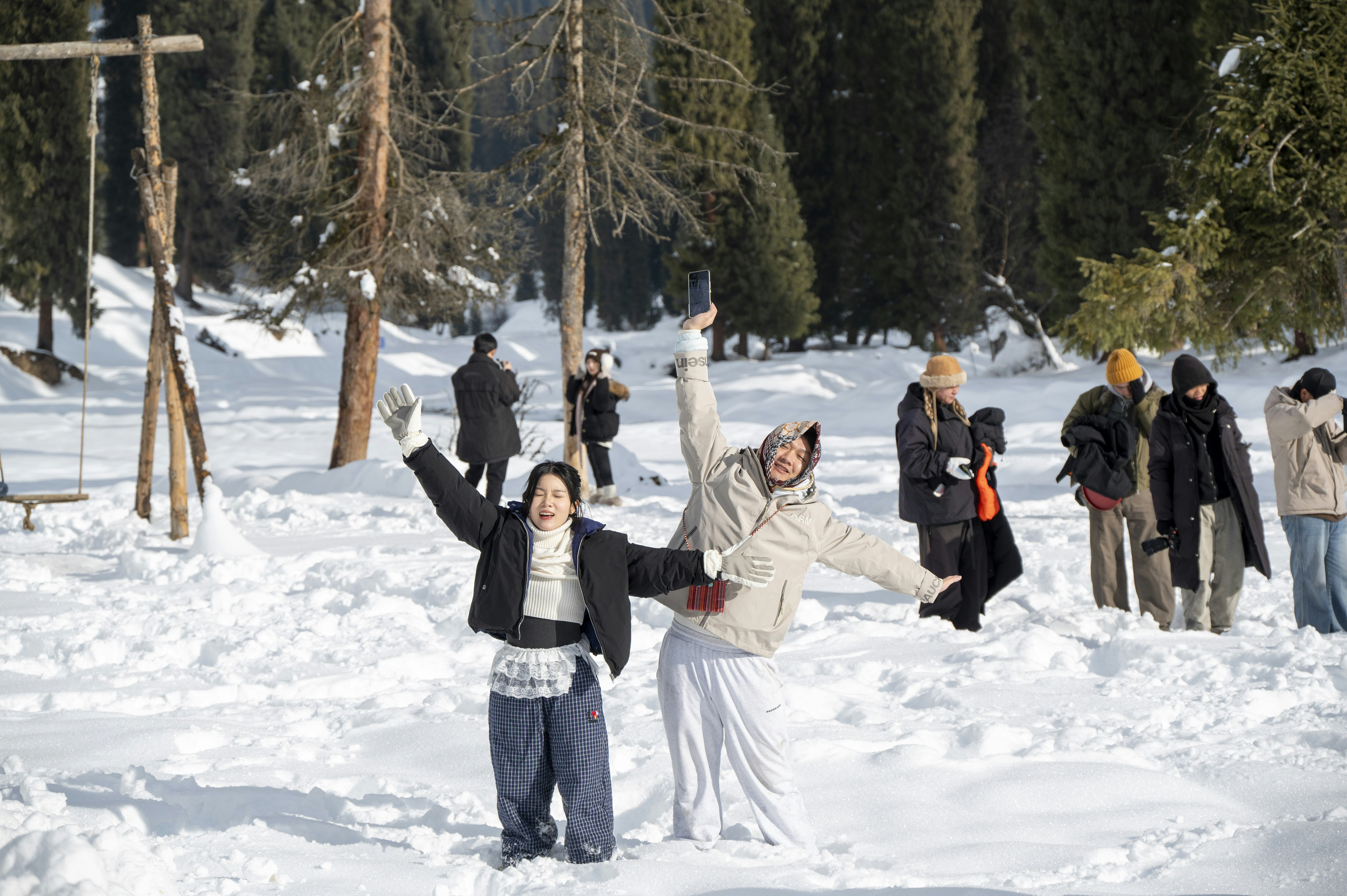 Two women throwing snow in a winter forest