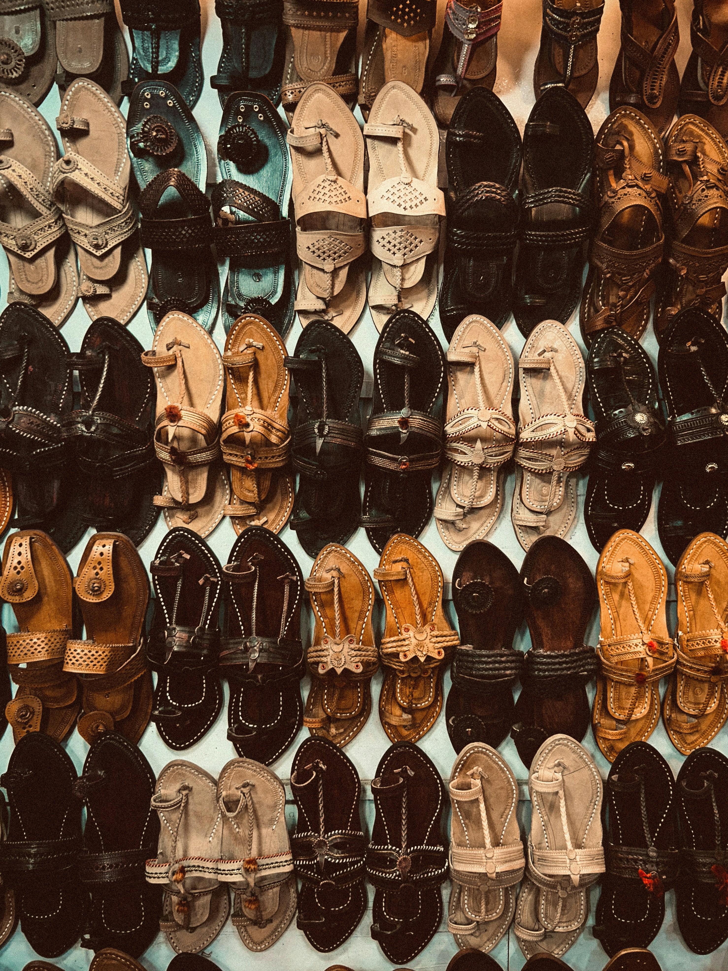 A wall of assorted leather sandals and shoes.
