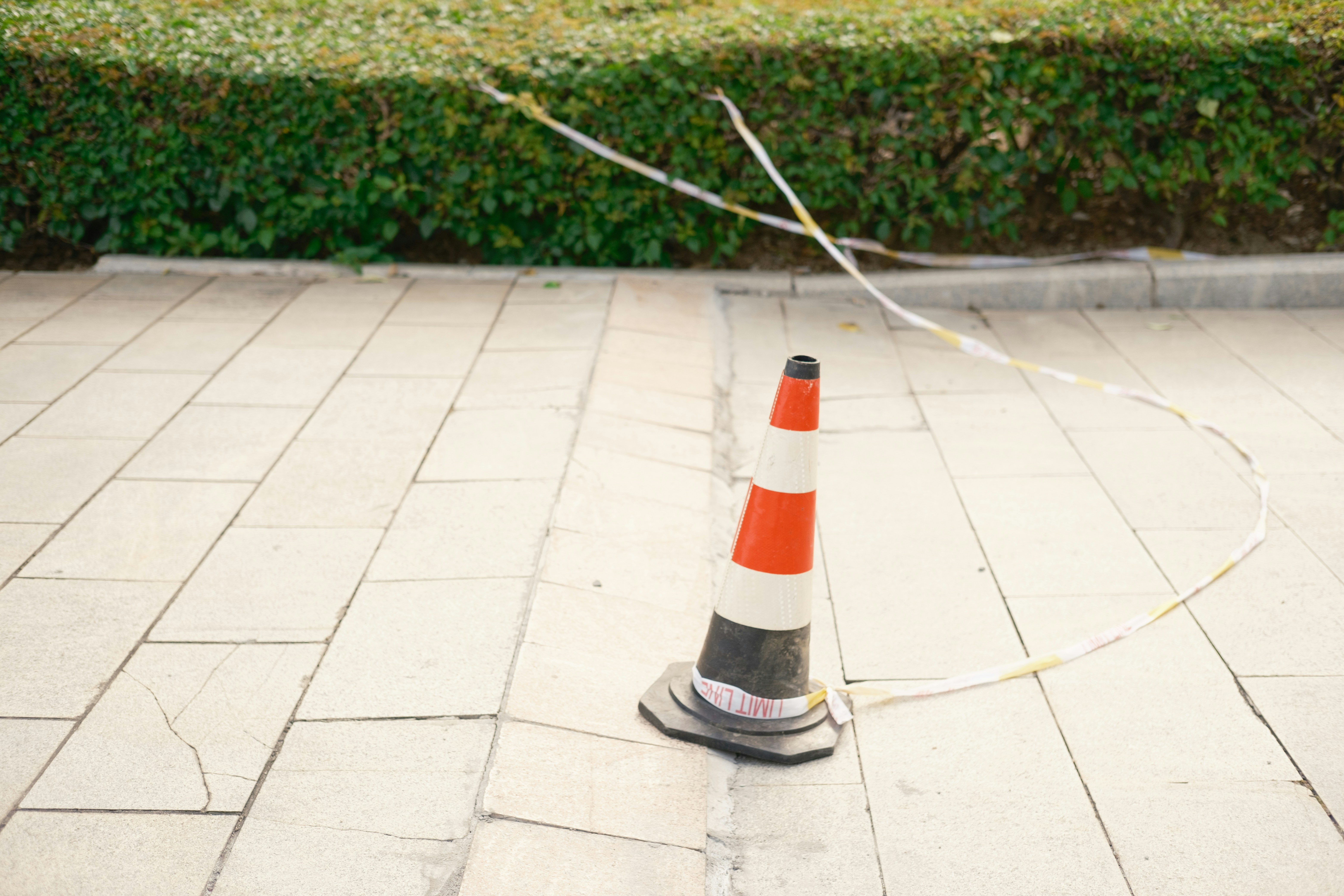 A traffic cone with tape on a paved surface