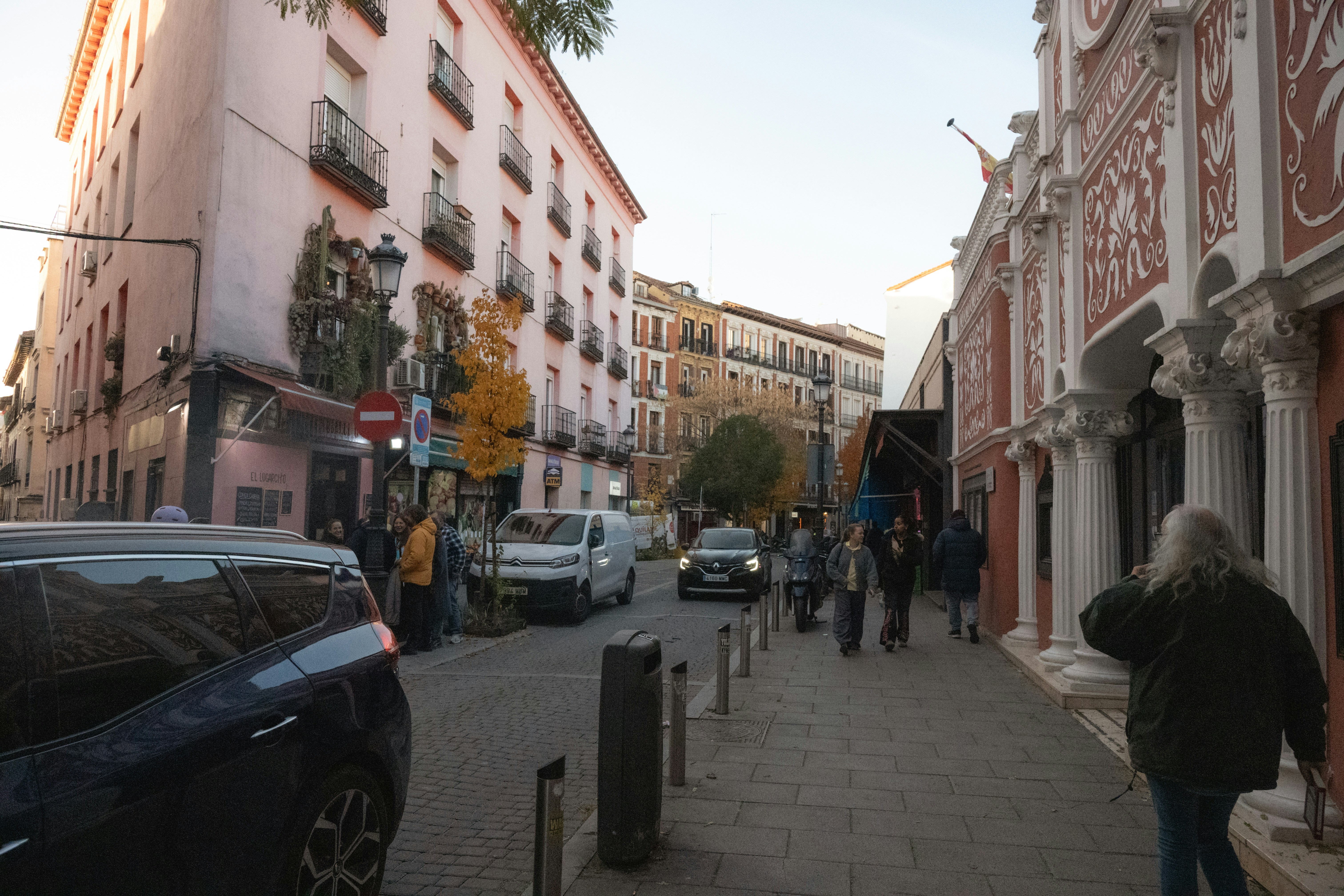 People walking down a street with buildings and cars.