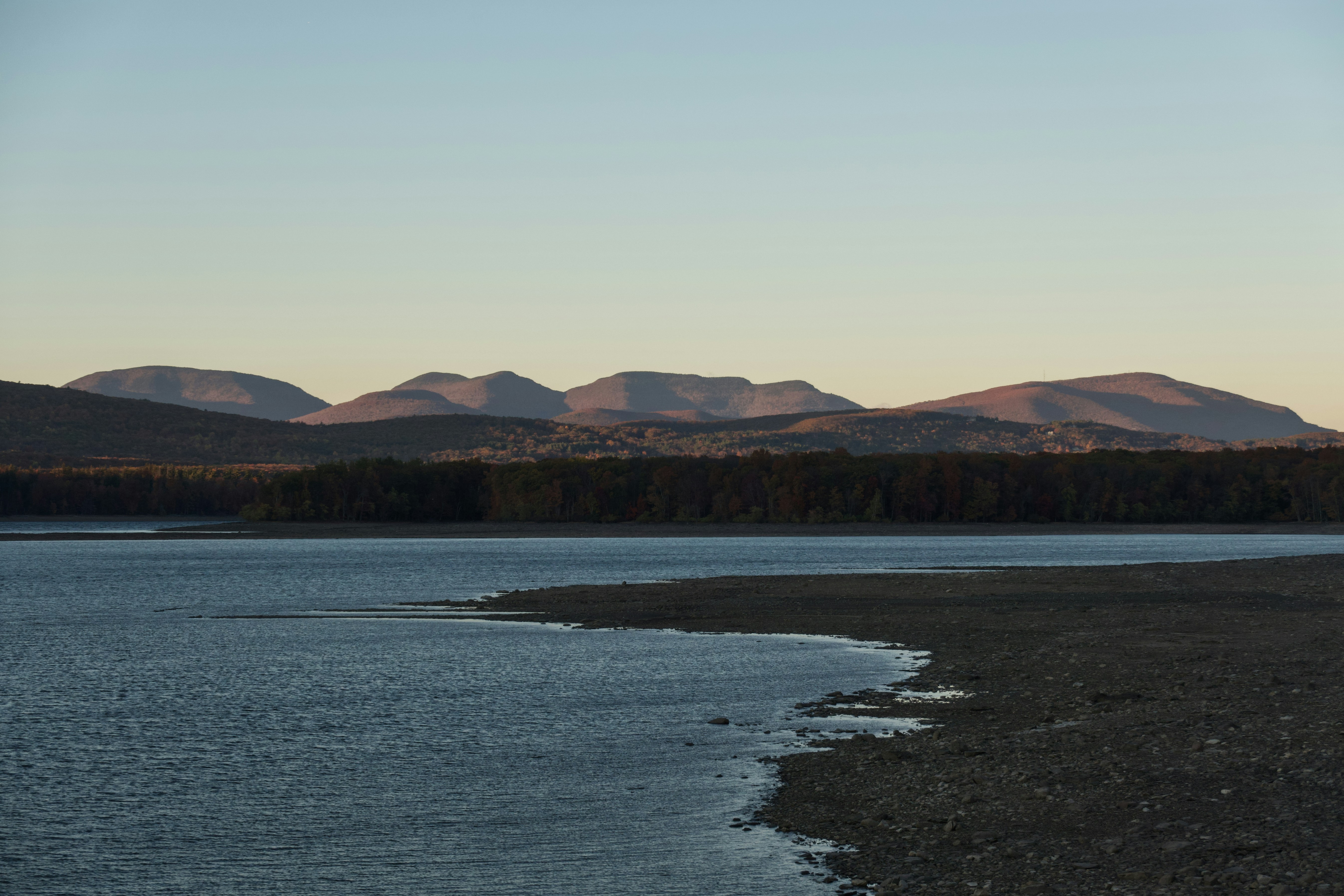 Calm lake water with distant mountains at sunset