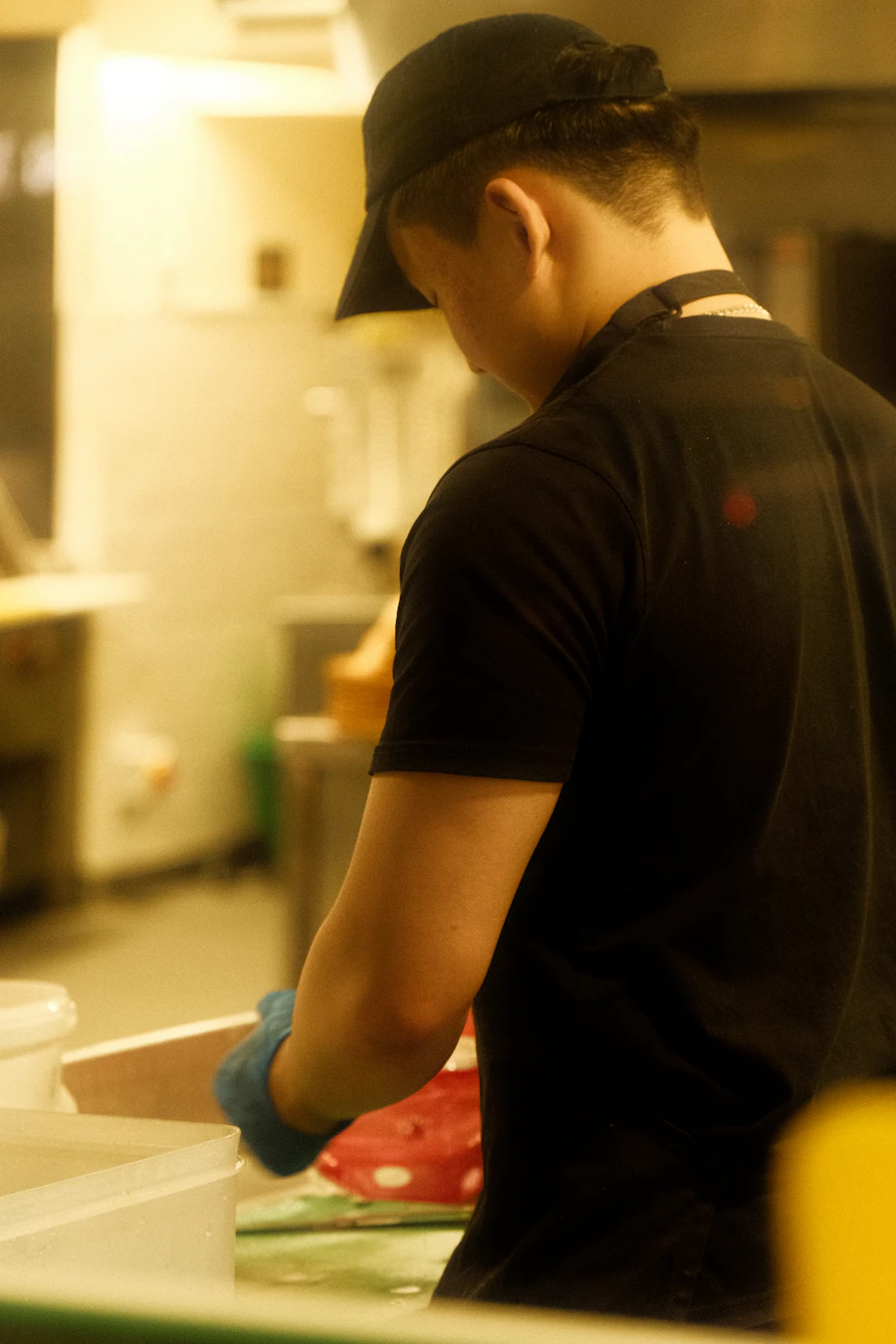 Kitchen worker in branded tee and cap on the line