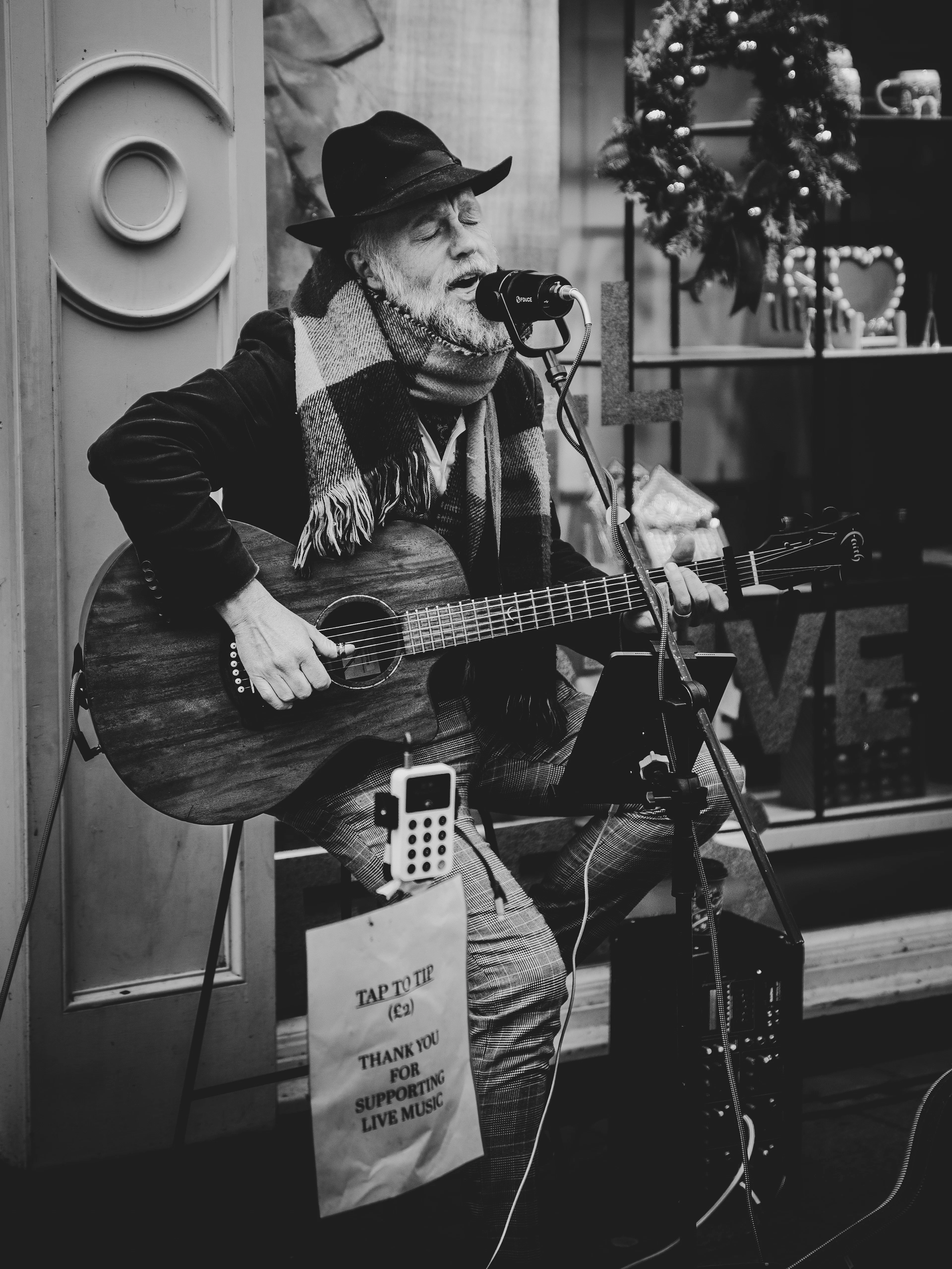 Street musician singing into a microphone with an Encore tip poster on his stand