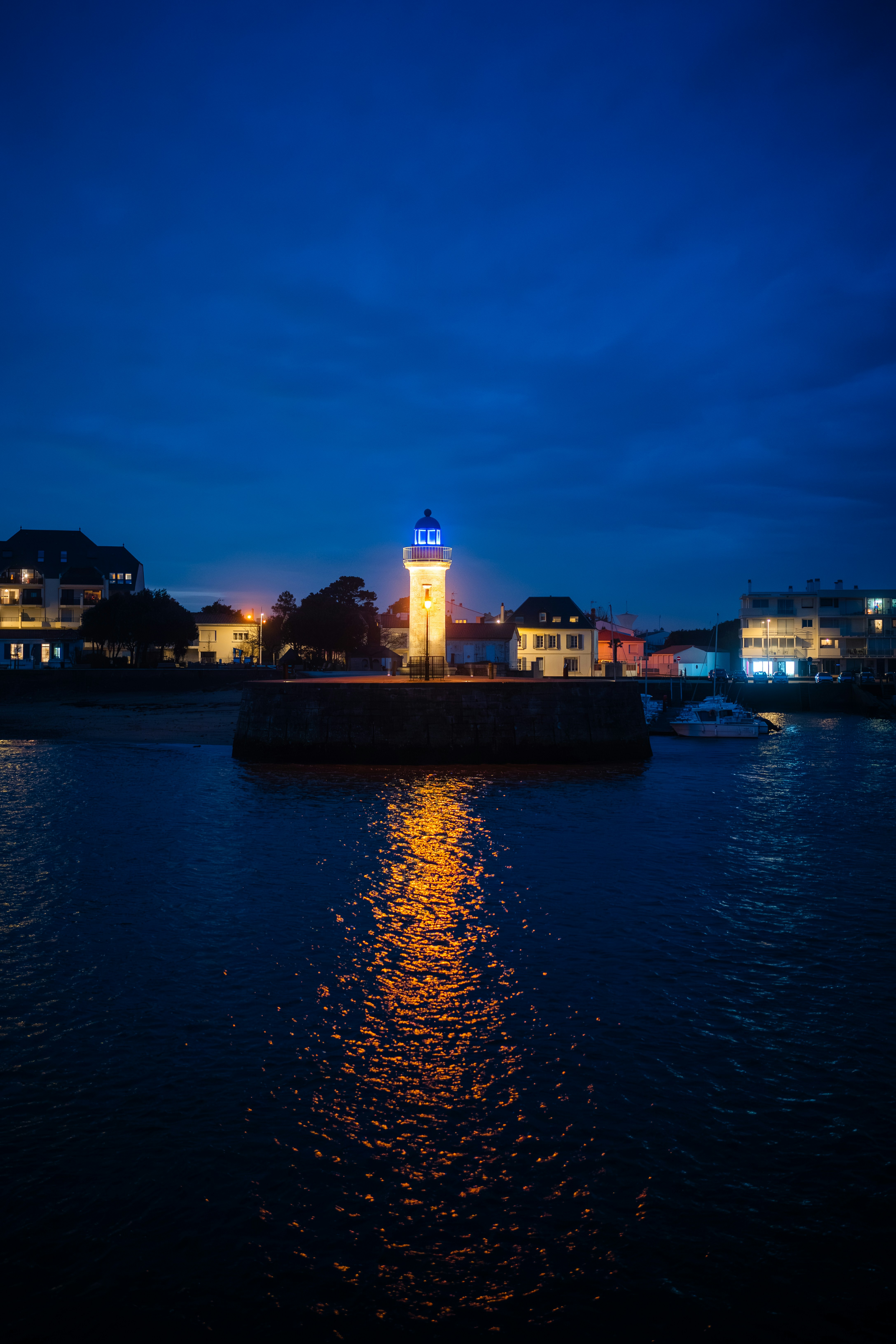 Lighthouse reflecting light on dark water at dusk