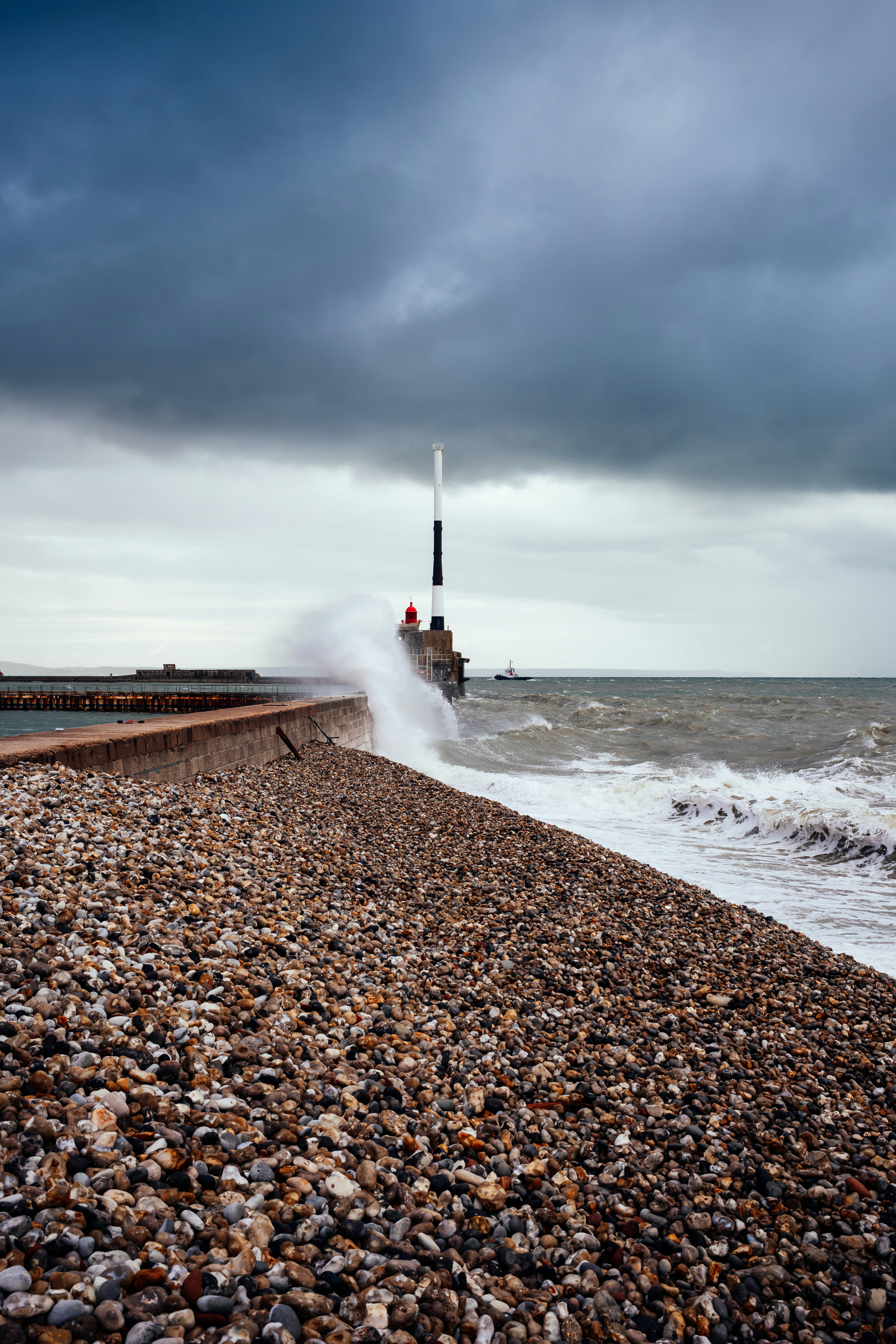 Waves crashing against a pier under stormy skies