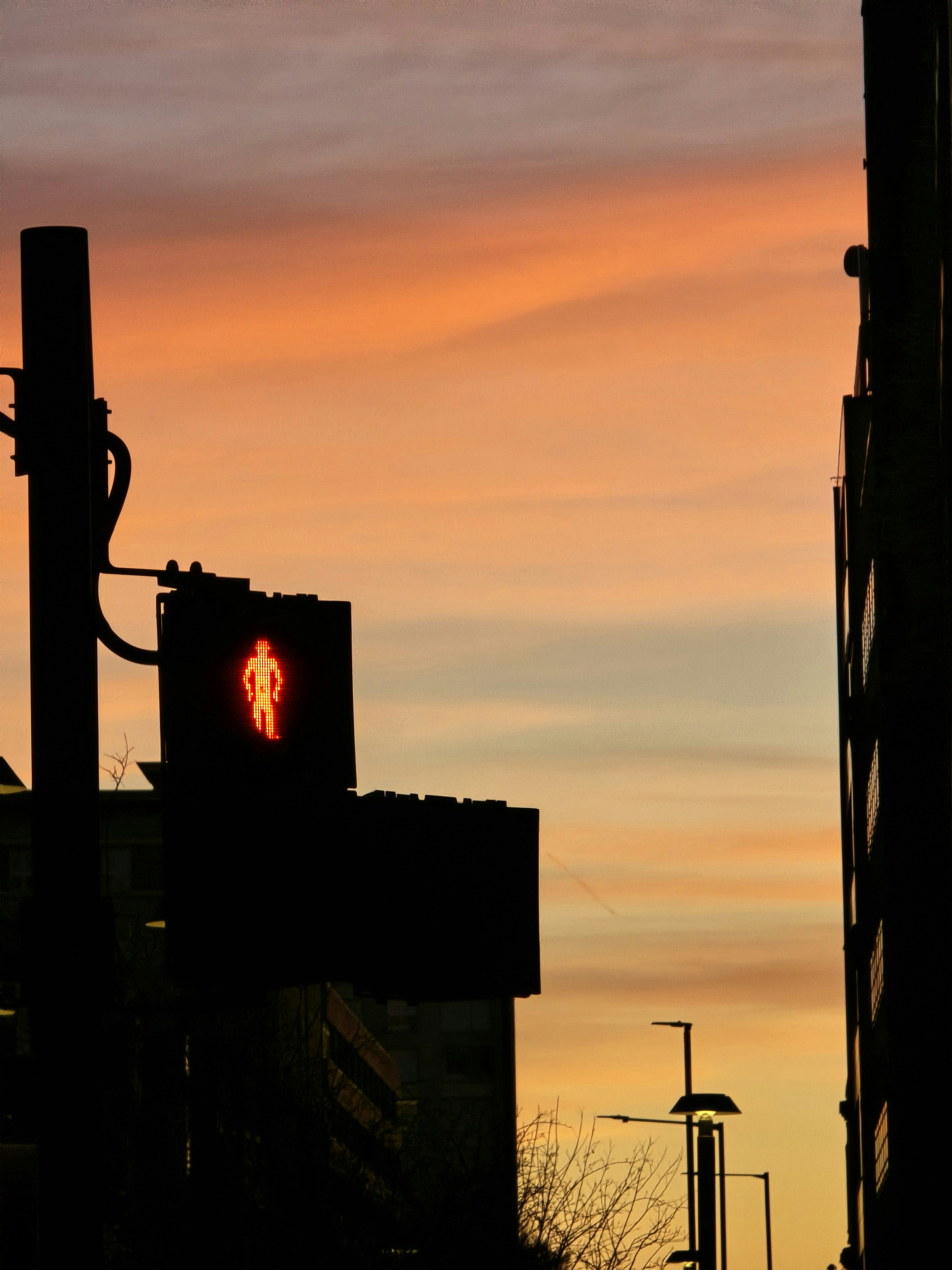 Silhouette of a pedestrian crossing signal at sunset