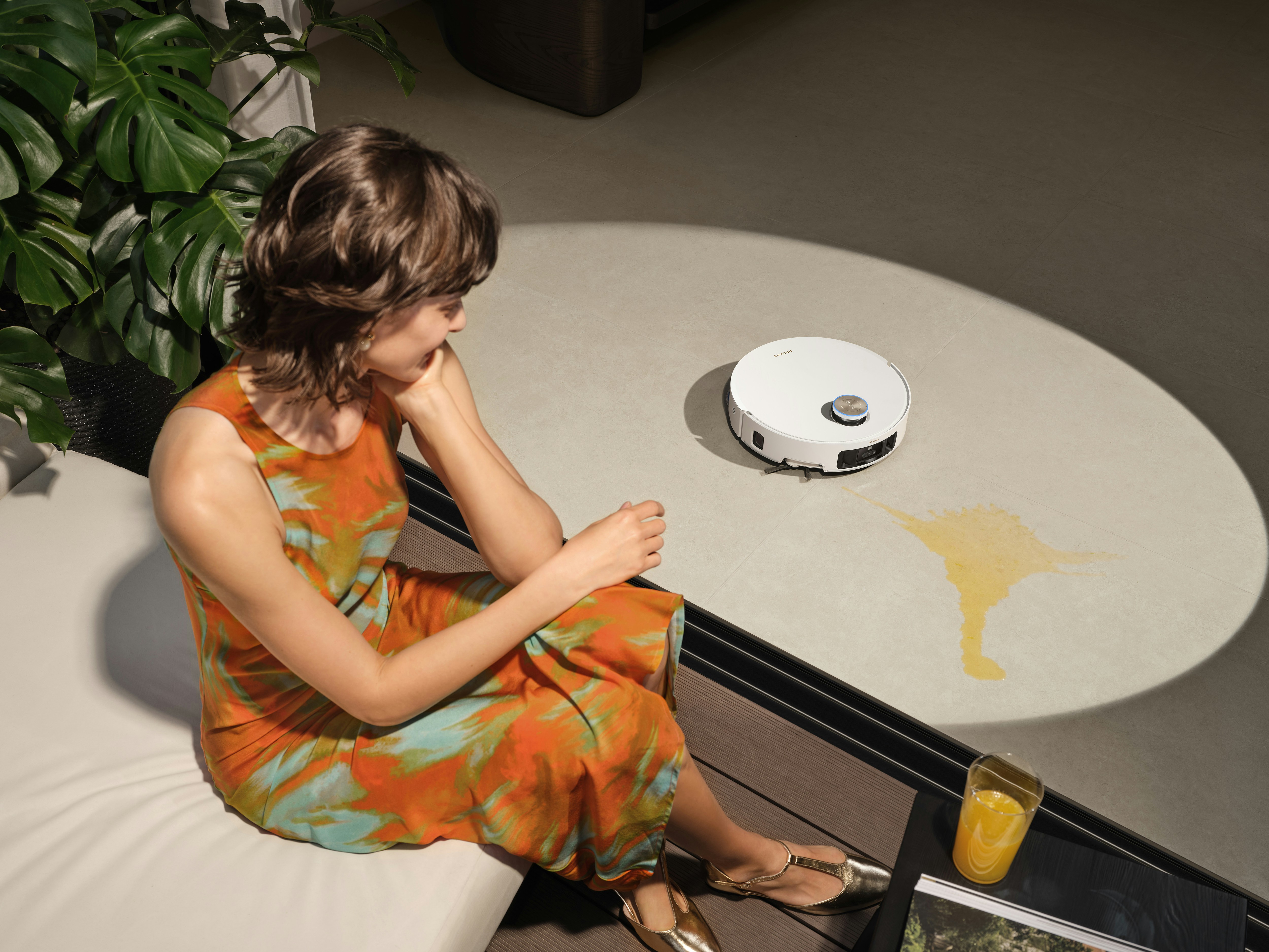 Woman watches robot vacuum clean spill on table