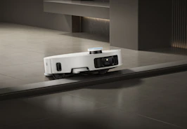 A white robot vacuum cleaner navigates a floor transition.