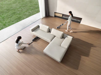 Two women cleaning a modern living room with vacuum cleaners.