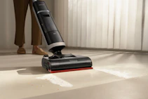 A person using a cordless vacuum cleaner on a floor.
