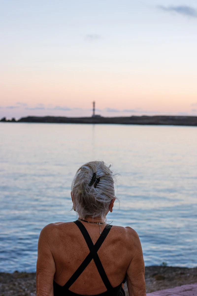 A woman watching the sunset by a lighthouse