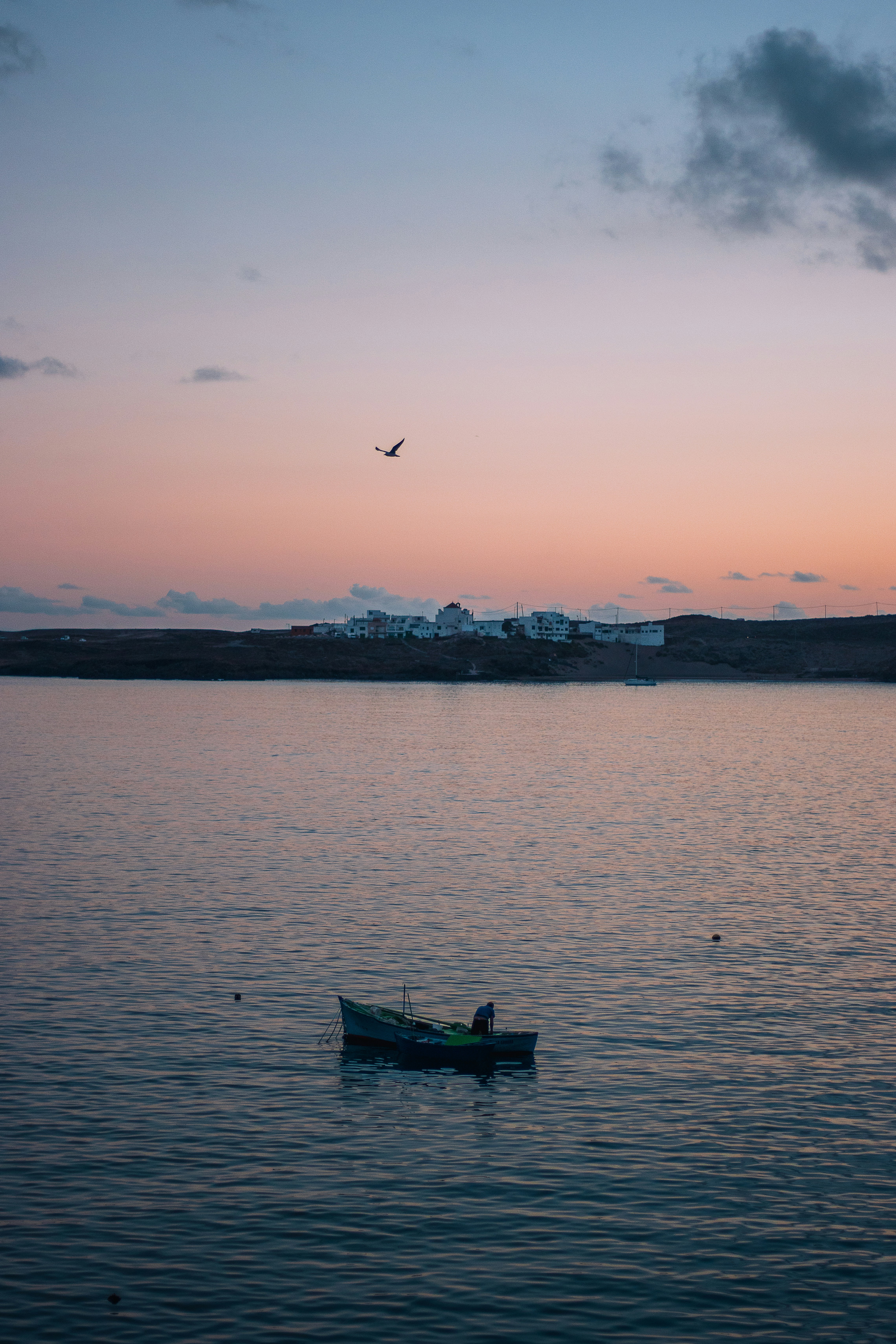 A lone boat on calm water at sunset.