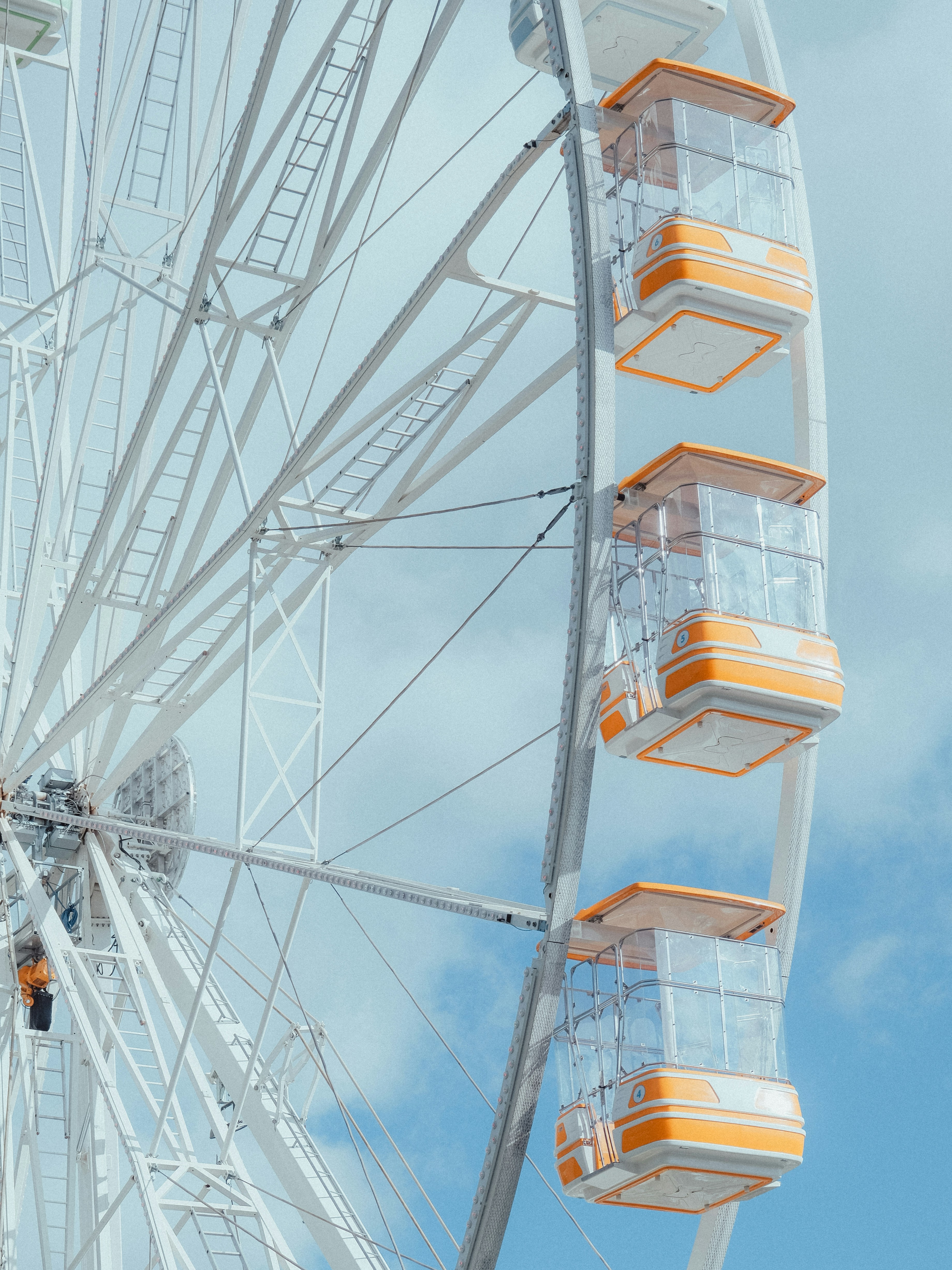 Weißes Riesenrad mit orangefarbenen und klaren Kabinen