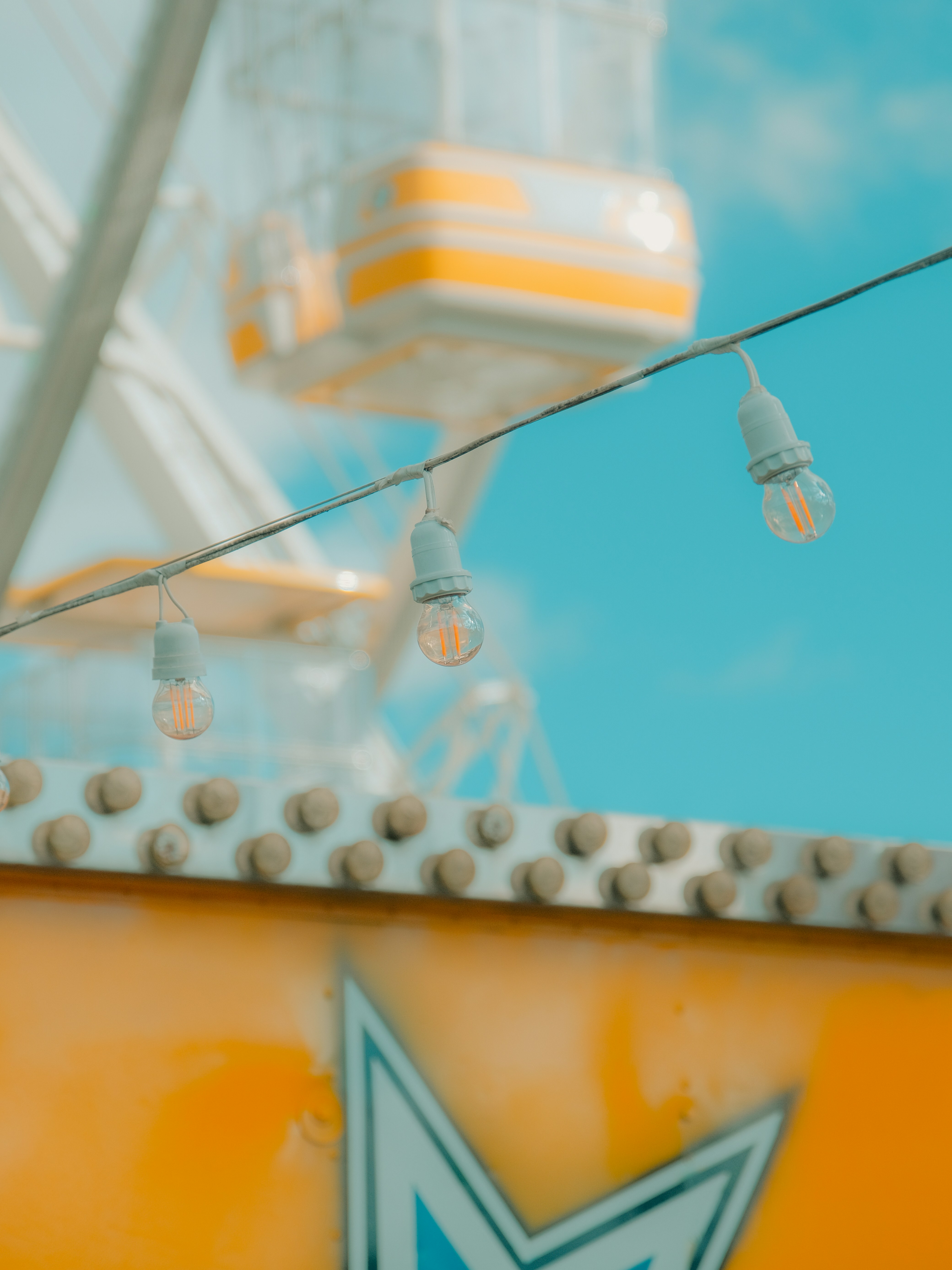 Riesenrad und Lichterketten vor blauem Himmel