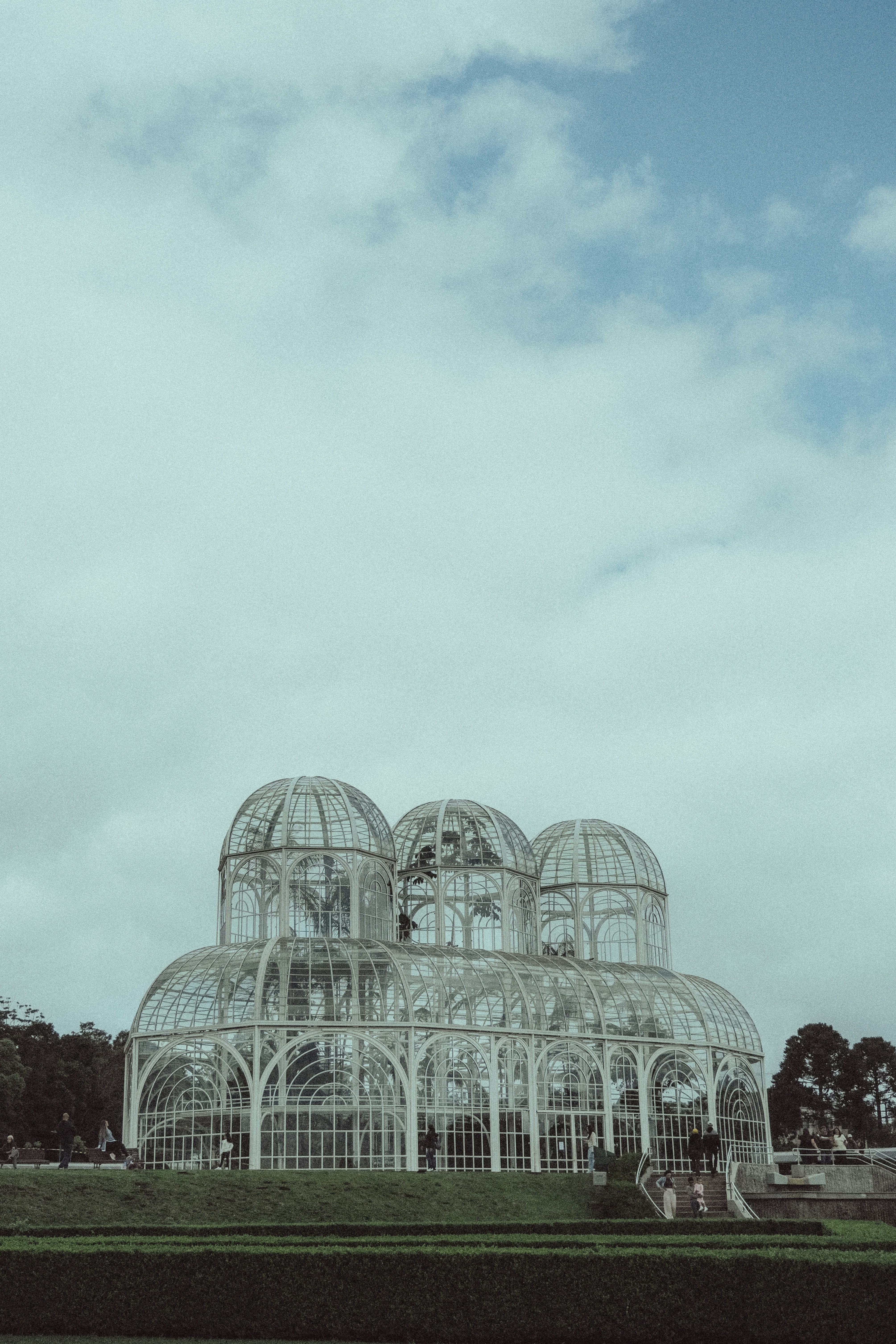 Glasgewächshaus mit mehreren Kuppeln vor wolkigem Himmel