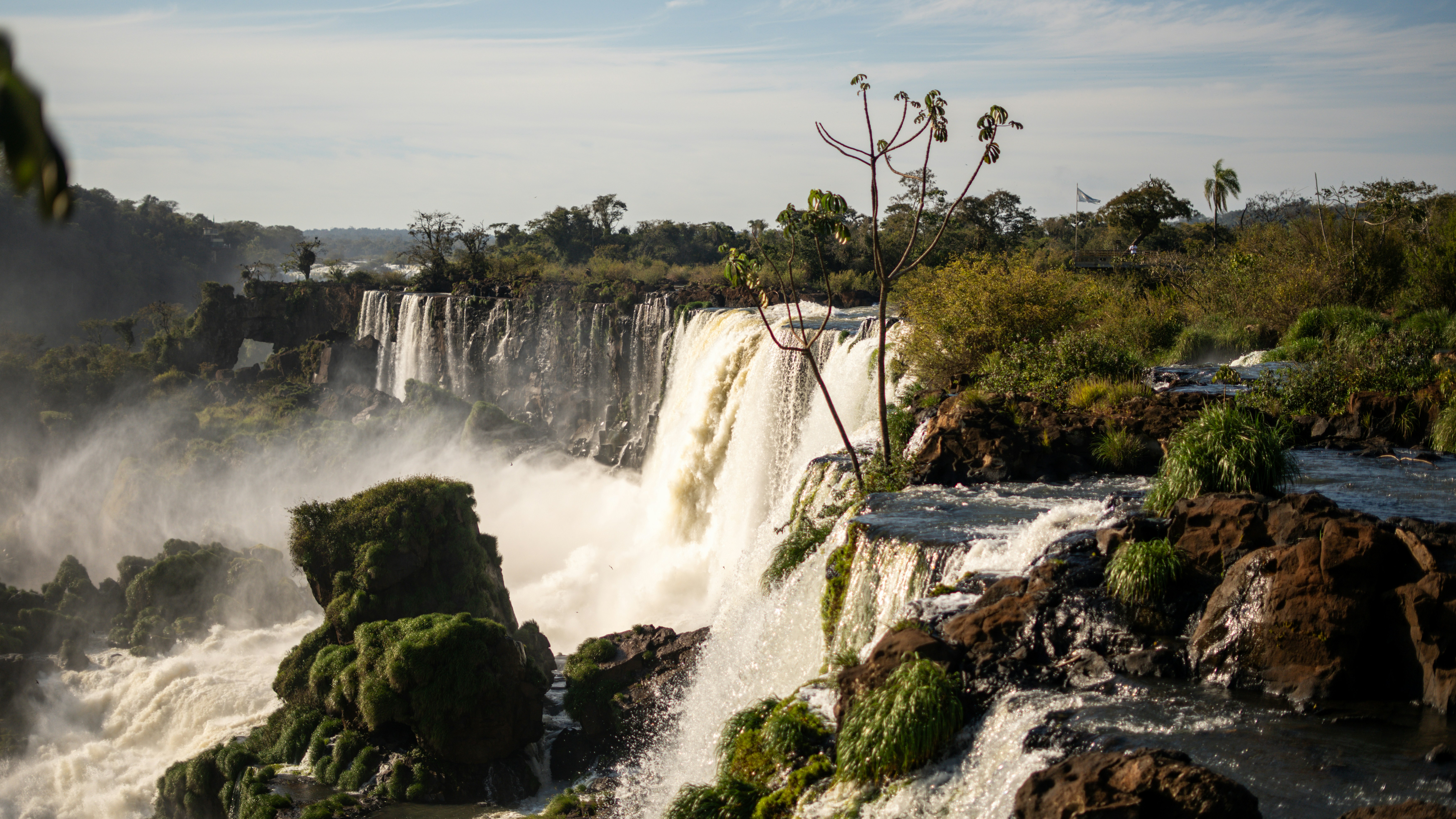 Powerful waterfalls cascade over rocky cliffs surrounded by lush greenery.