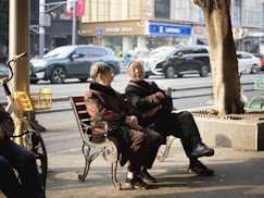 Two elderly people sitting on a park bench.