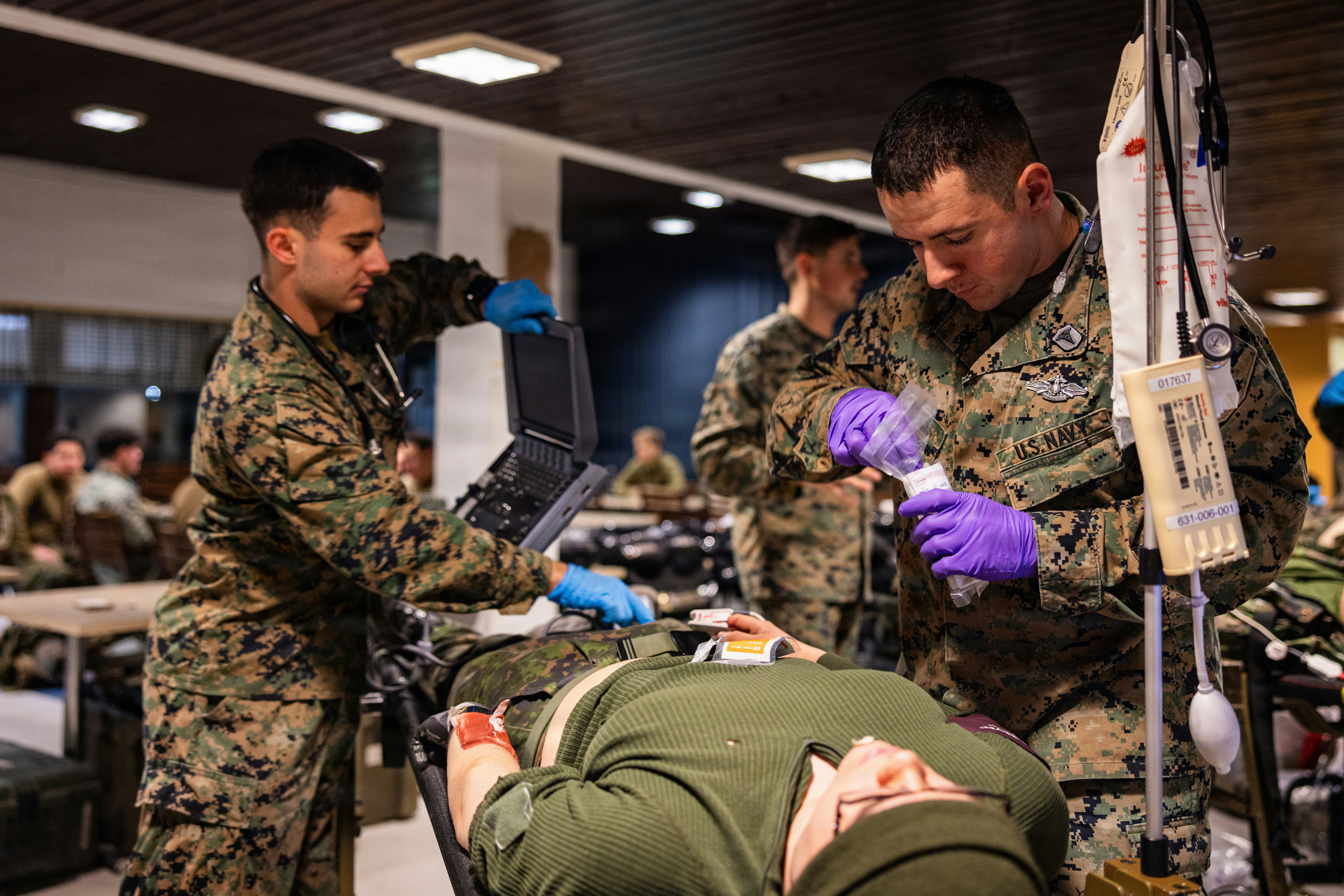 Marines provide medical care to a patient on a stretcher.