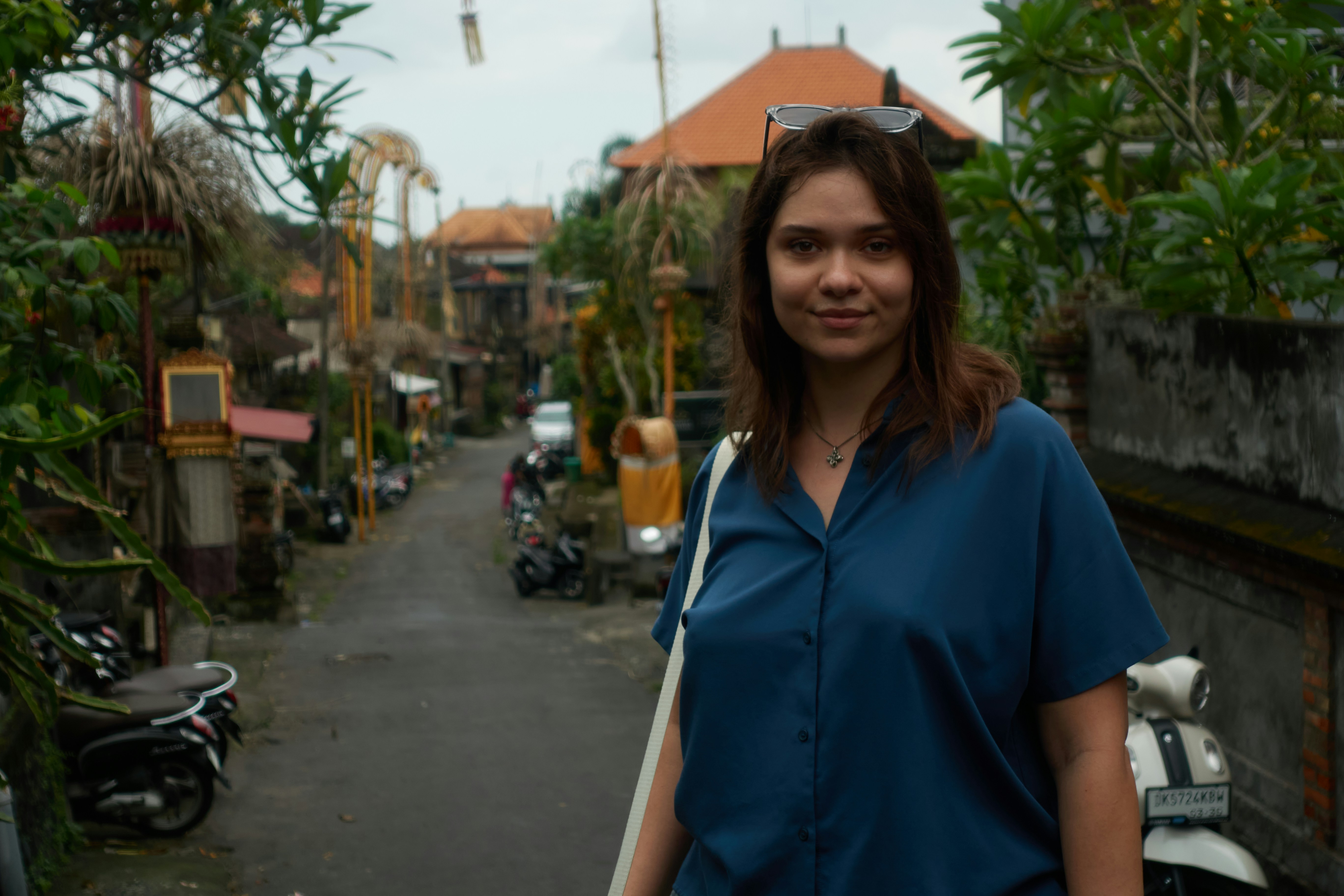 Wanita muda berdiri di jalan di sebuah desa.