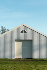 A light gray barn with a large door.