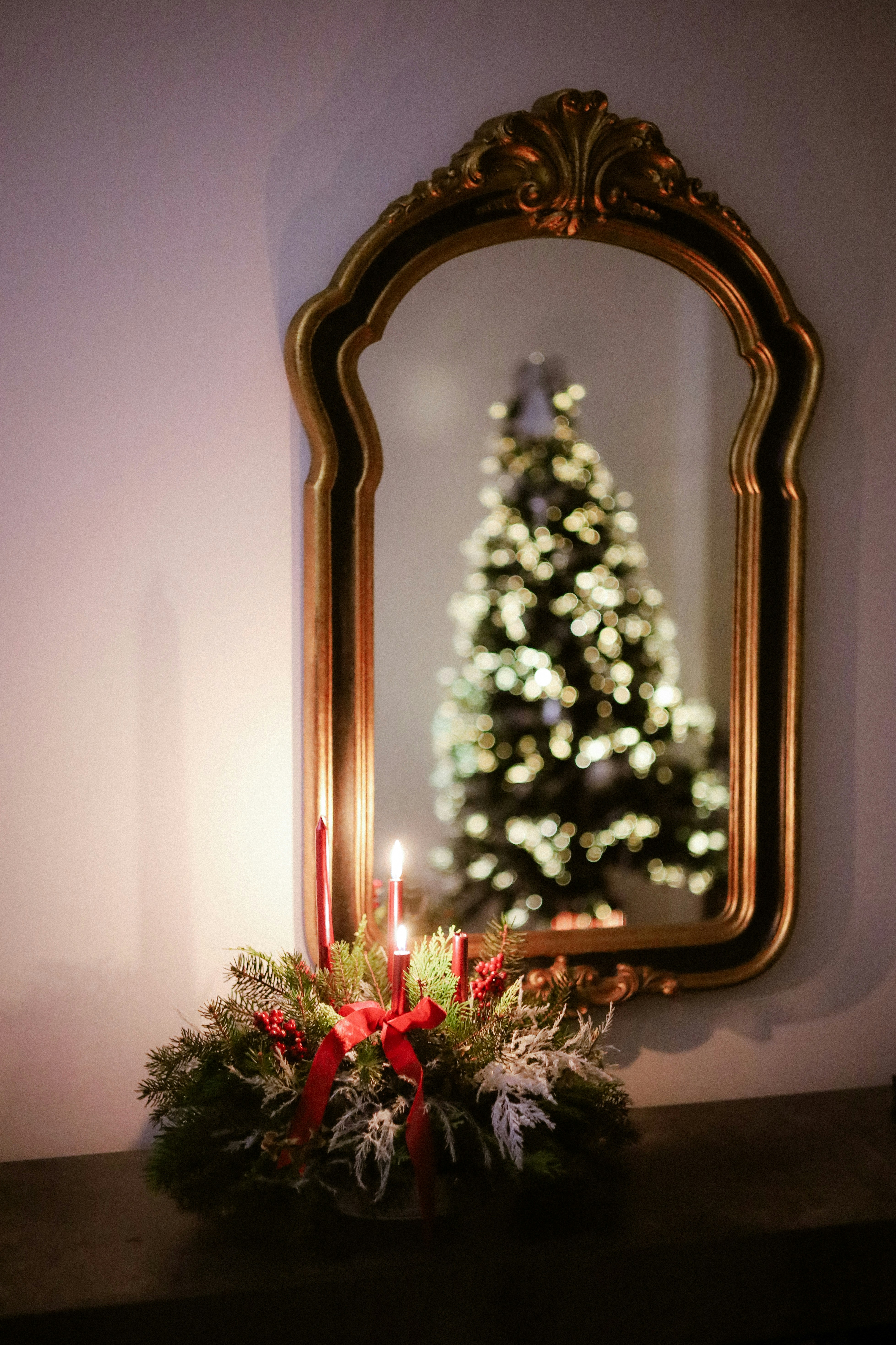 Christmas tree reflection in ornate mirror with candles.