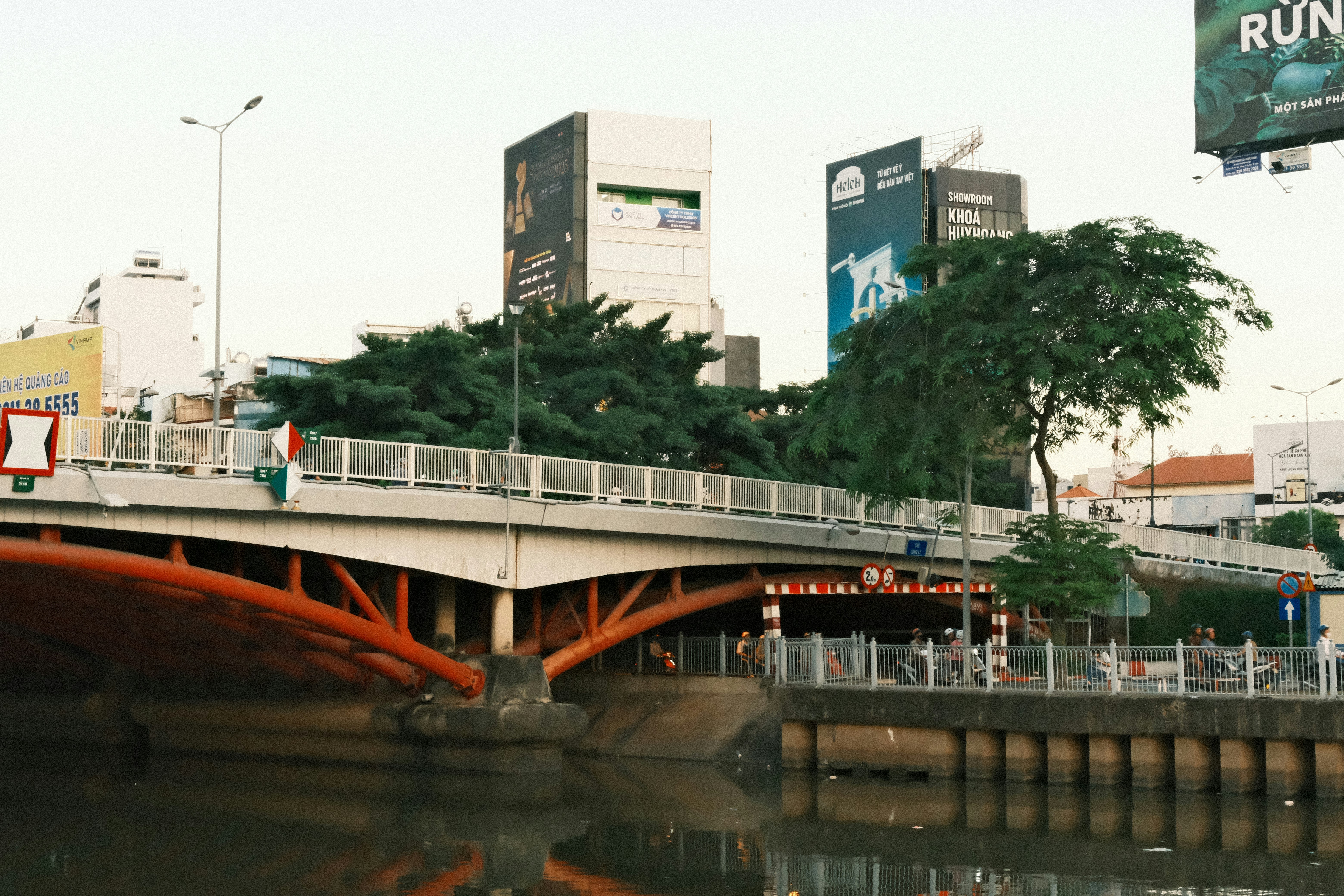 Orange bridge over a canal with city buildings.