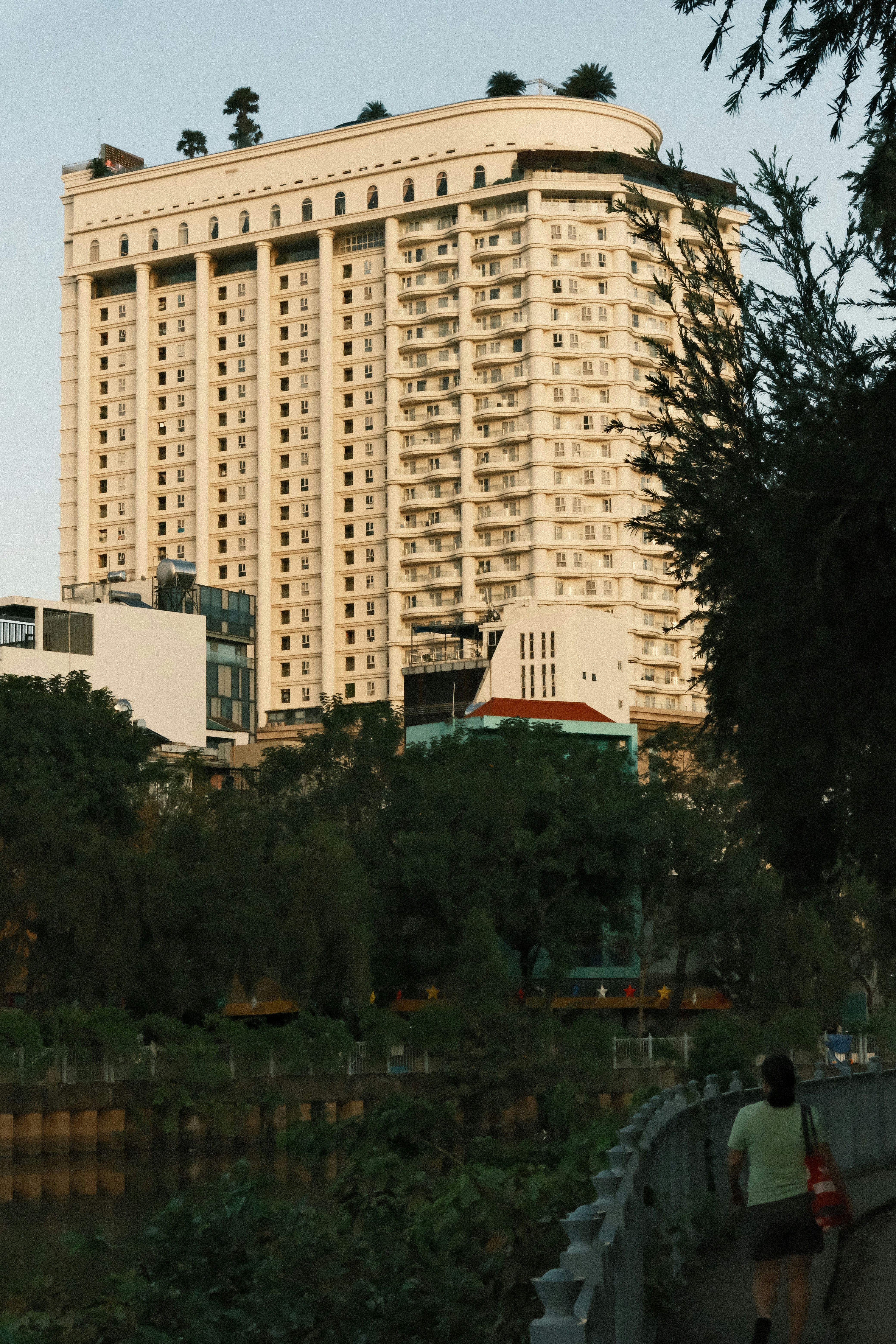 Tall modern building with many balconies and trees.