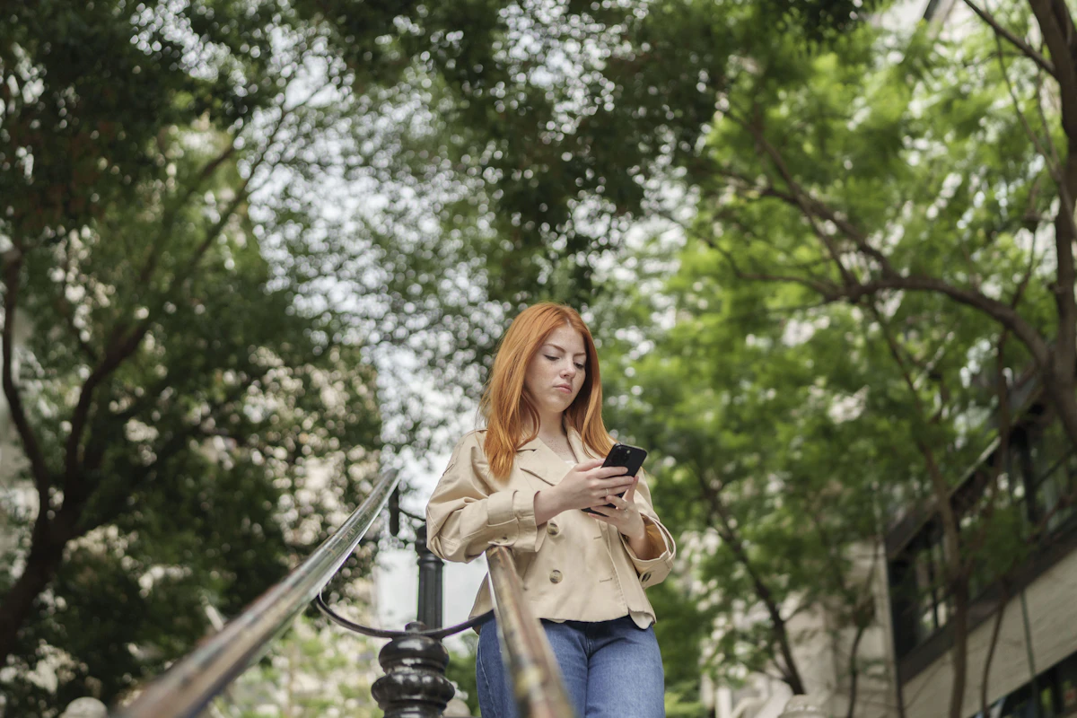 Woman with red hair using a smartphone outdoors