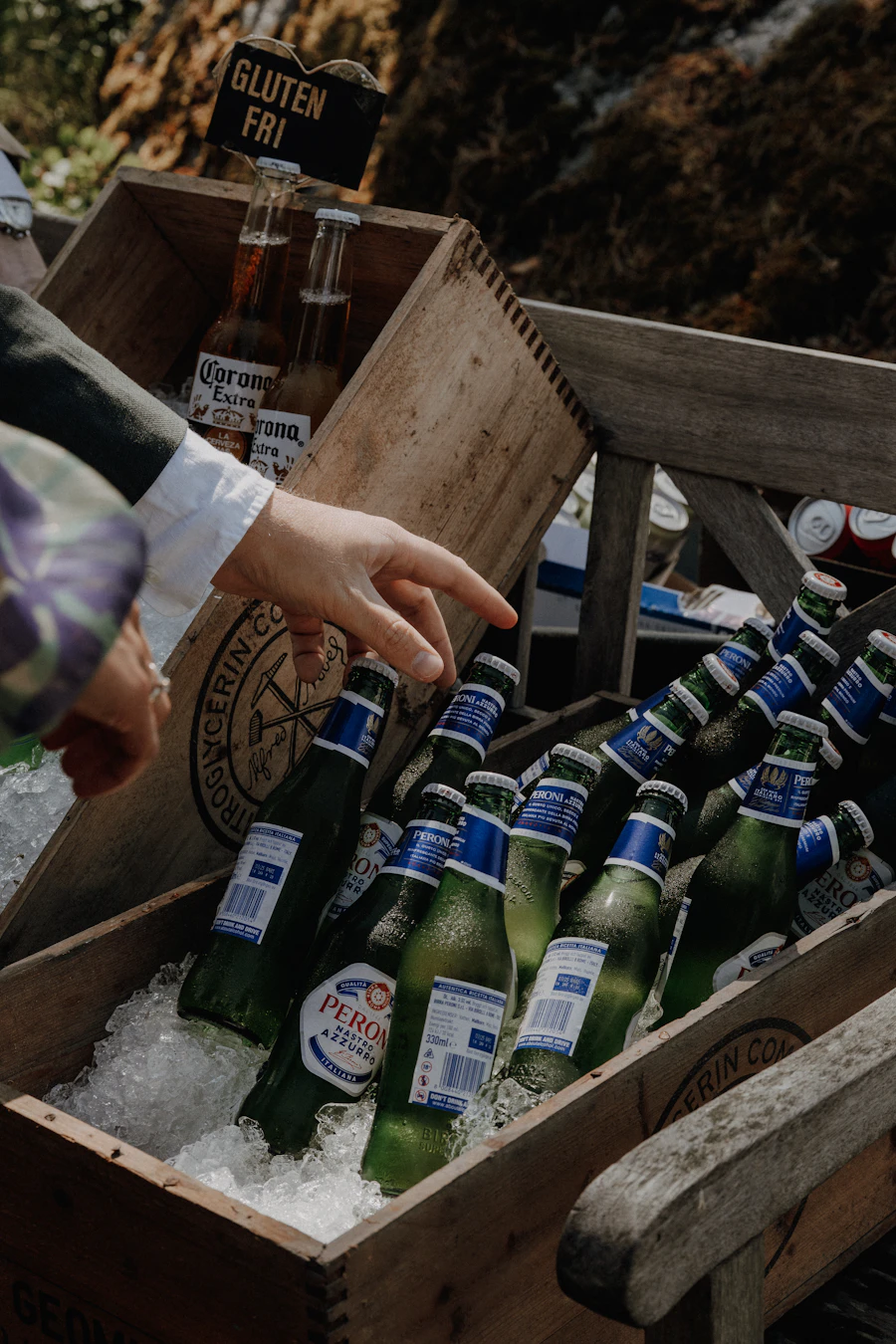 Bottles of beer chilling in ice in wooden crates at an outdoor event -- the ideal setting for custom coozies