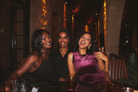 Three friends laughing at a table at night
