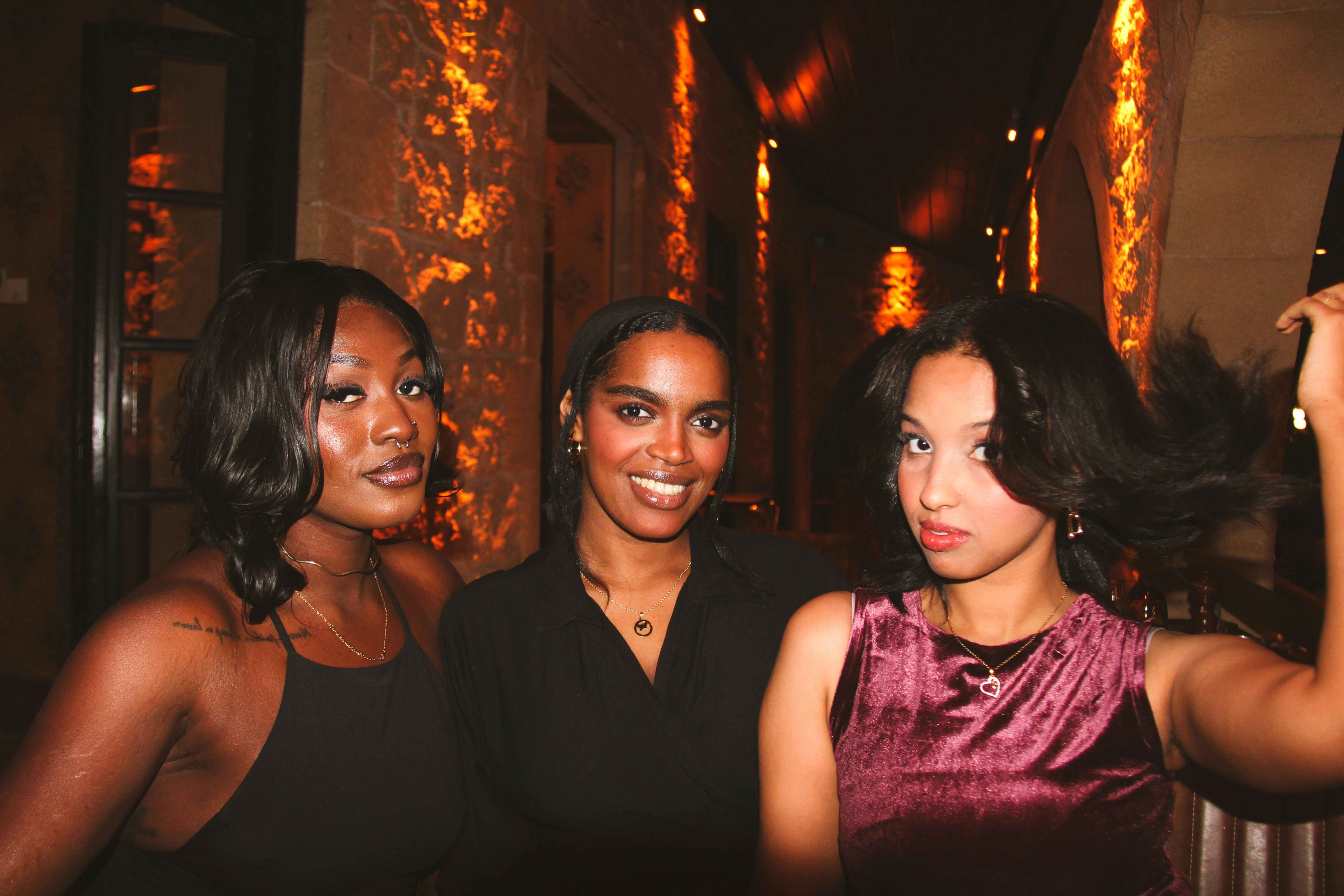 Three women posing for a picture at night