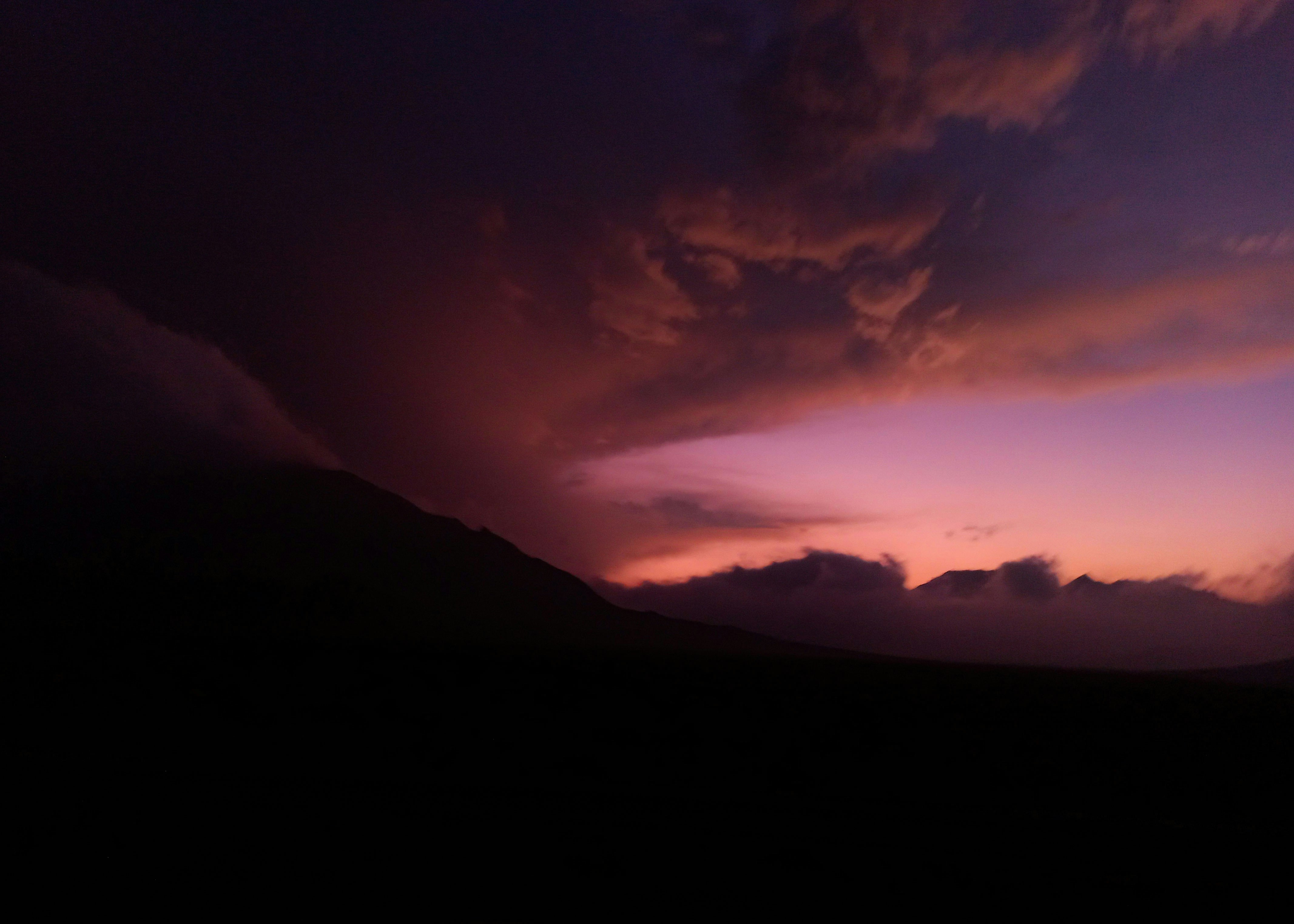 Dramatic sunset sky over dark mountains.