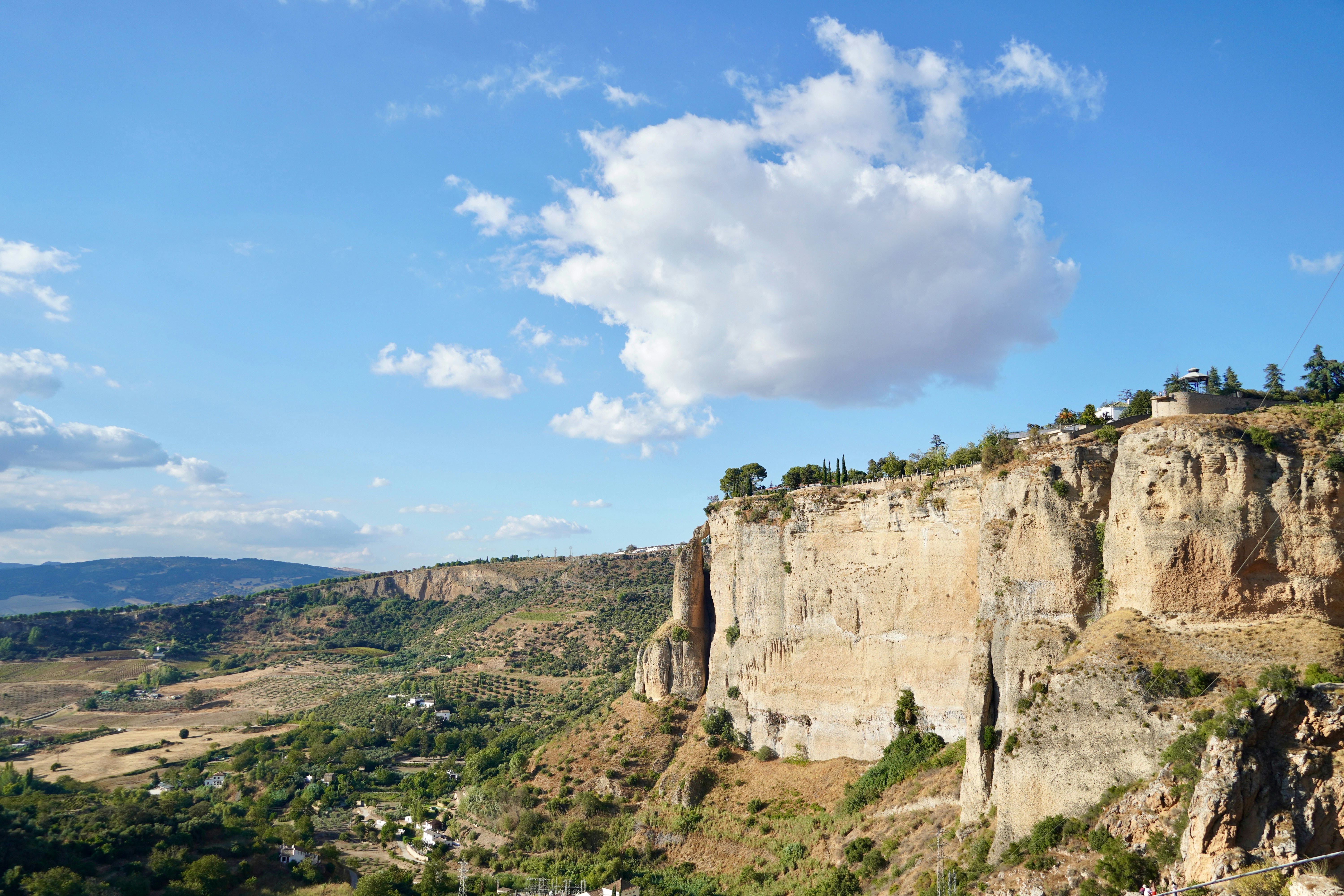 A dramatic cliff face under a bright blue sky.
