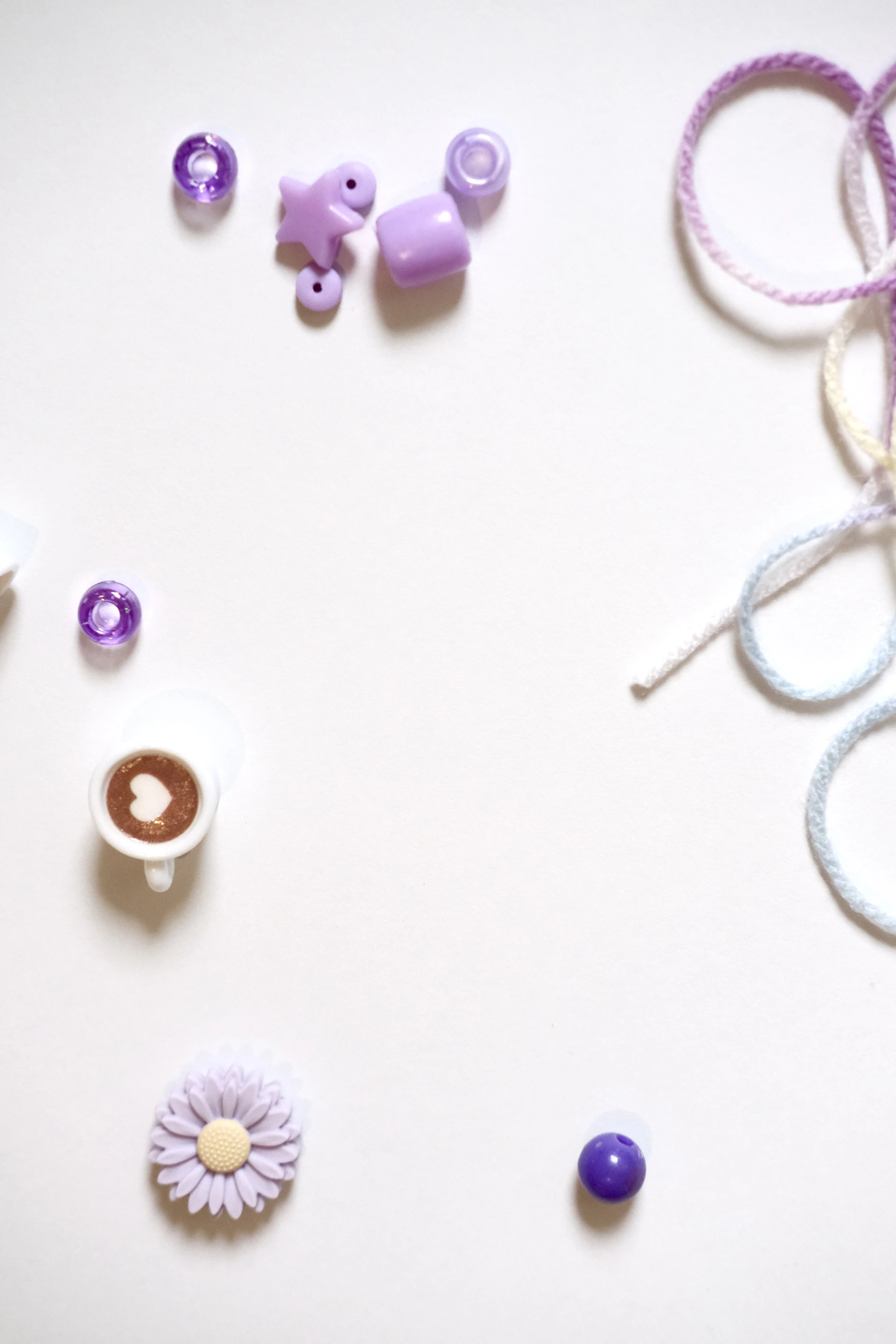 Purple beads, charms, and yarn on white background