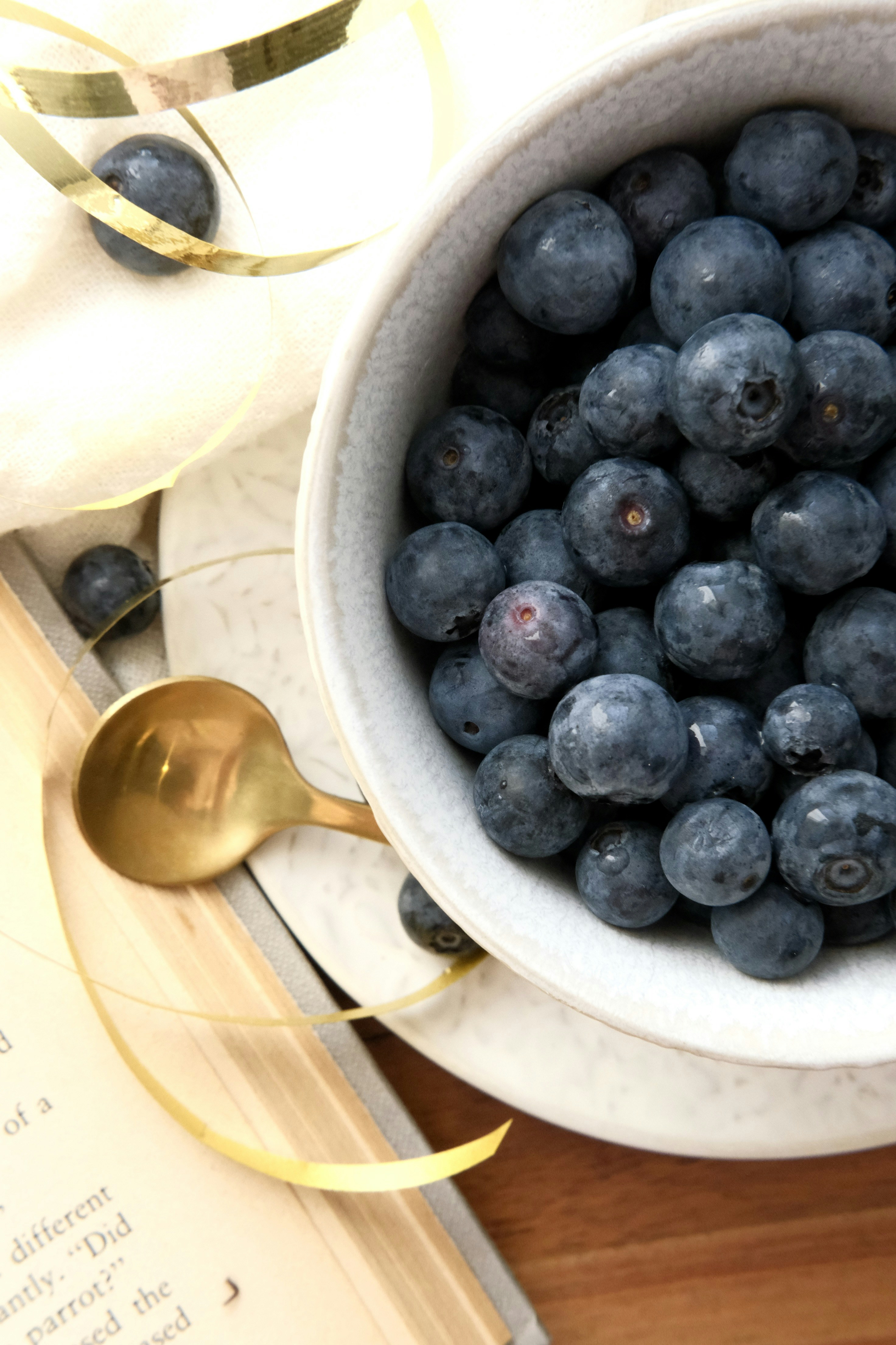 Bowl of fresh blueberries with a golden spoon.