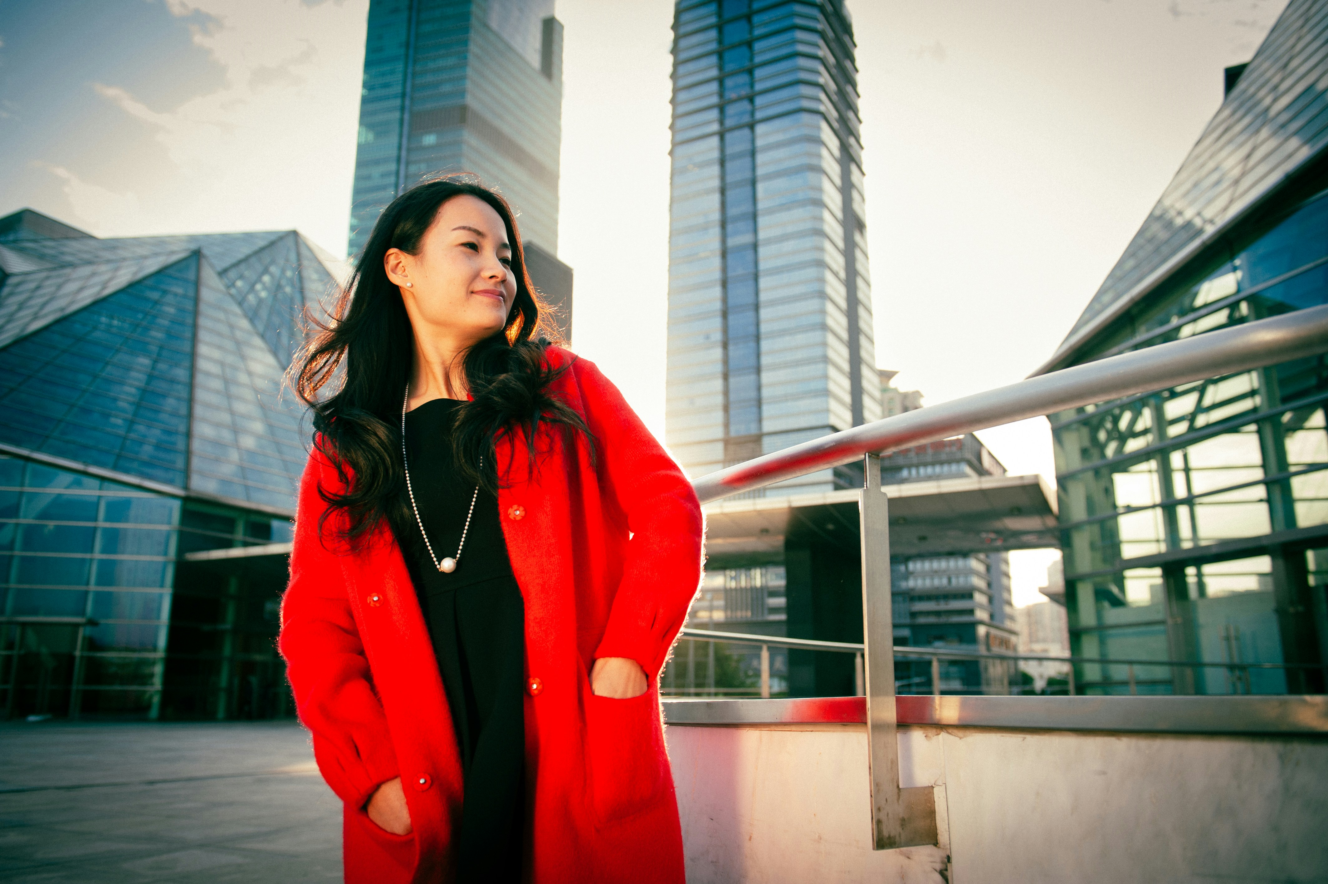 Woman in red coat standing near modern buildings
