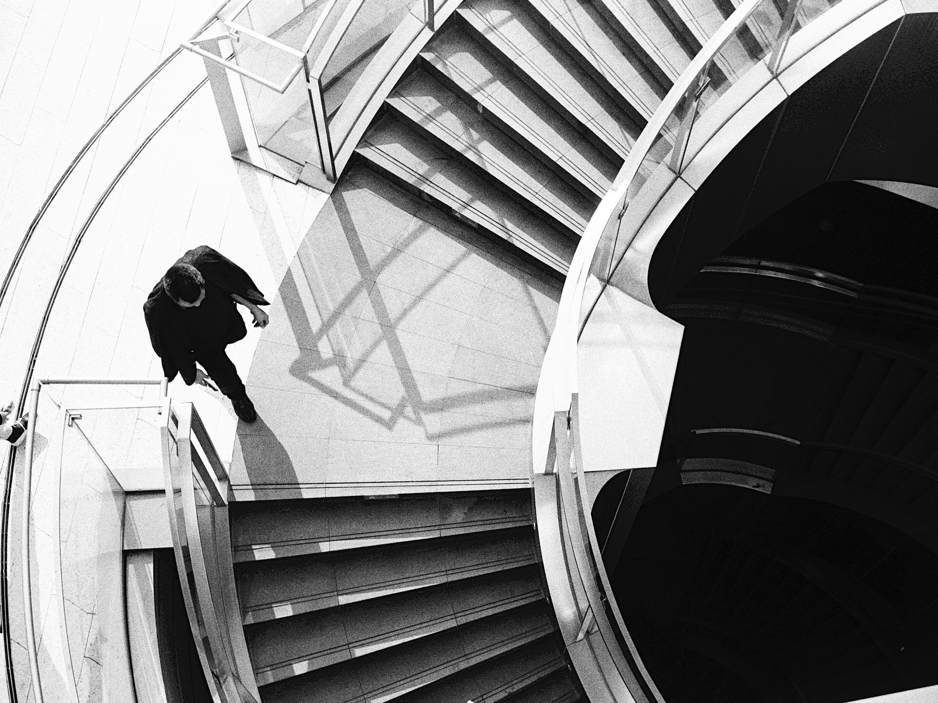 A man walks down modern spiral stairs.