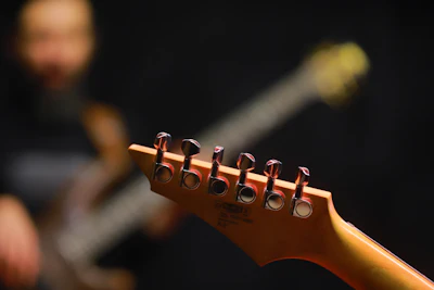 Close-up do cabeçote de uma guitarra elétrica com as tarraxas e cordas visíveis
