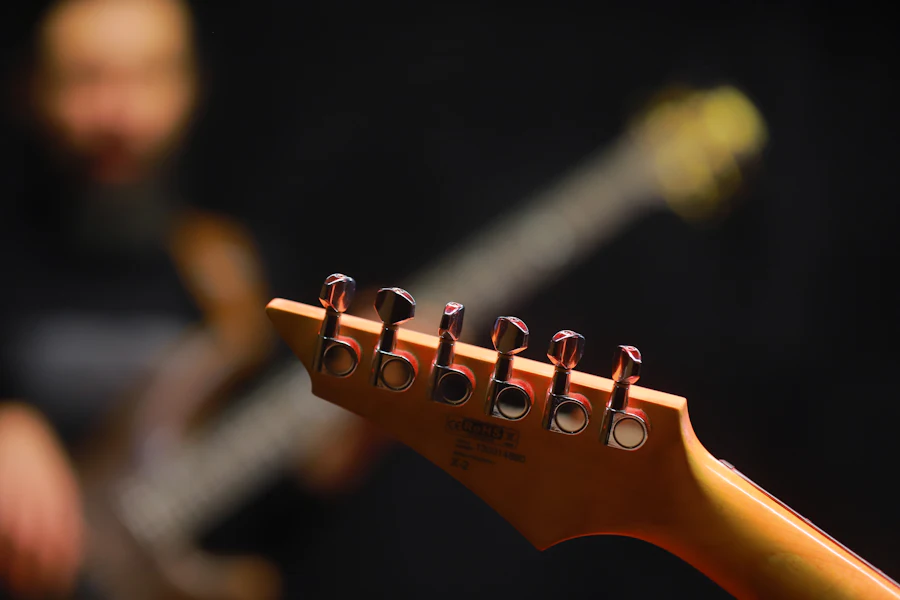 Close-up do cabeçote de uma guitarra elétrica com as tarraxas e cordas visíveis