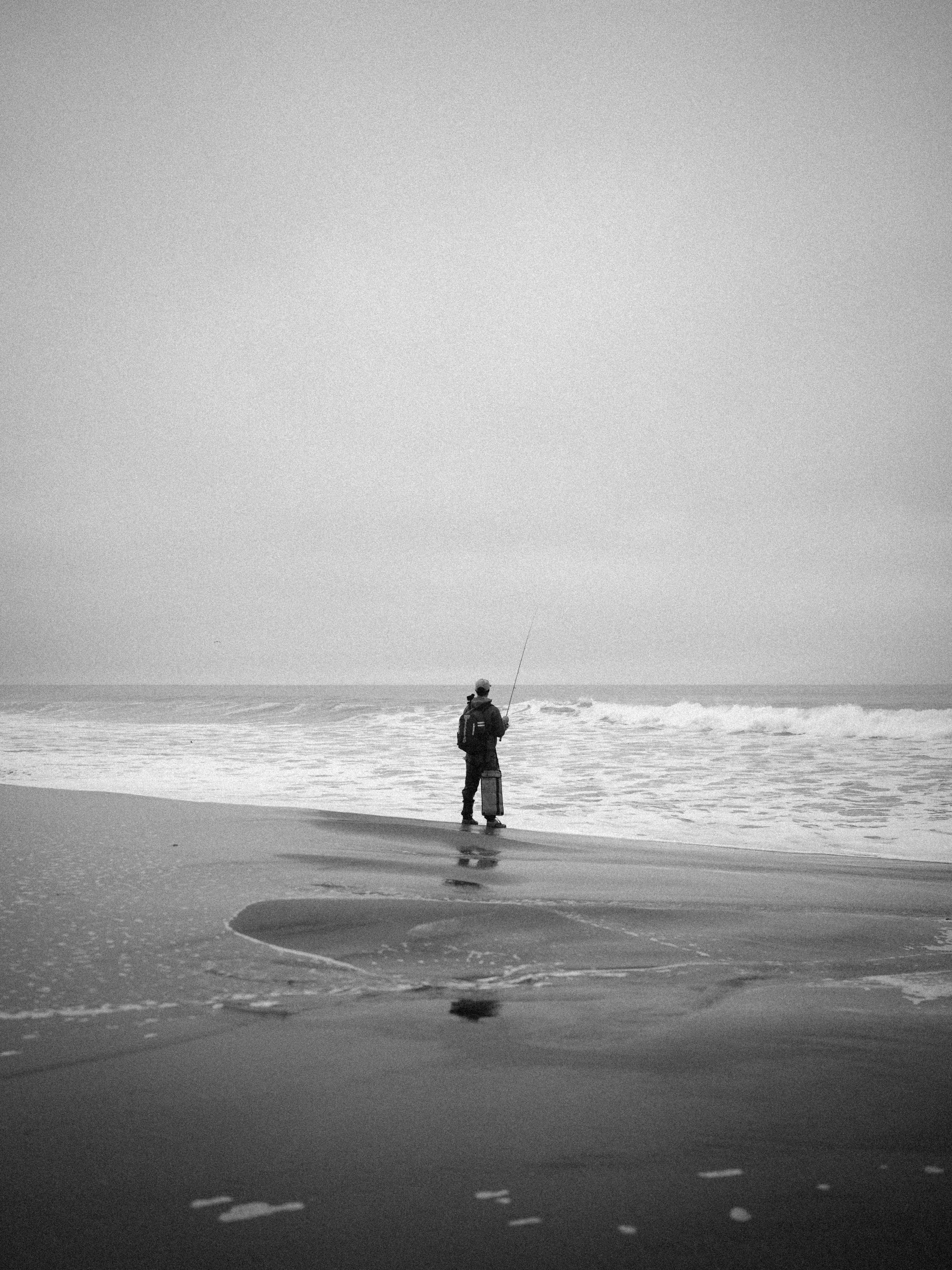 Fisherman casting line on a foggy beach