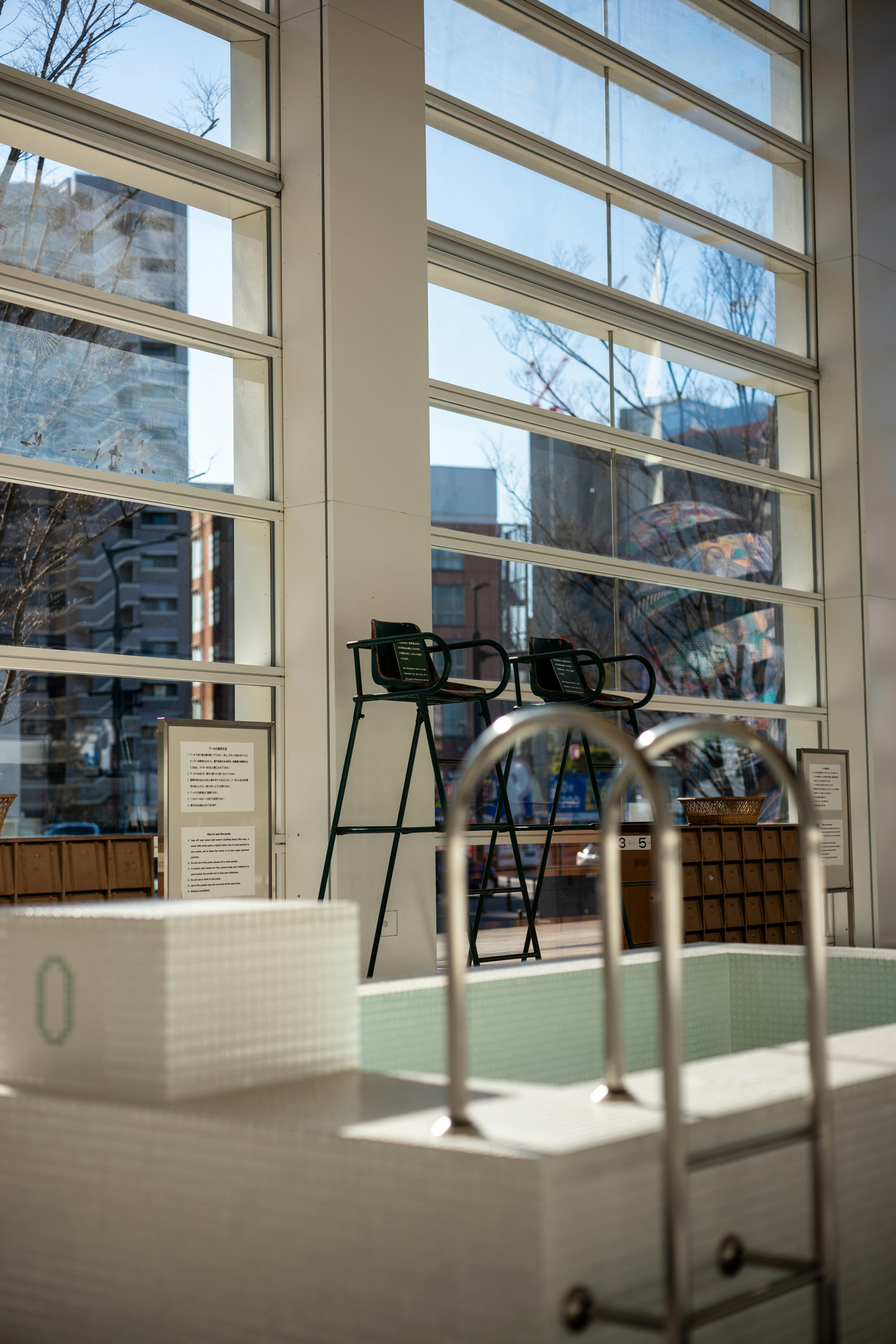 Two chairs by a pool with large windows