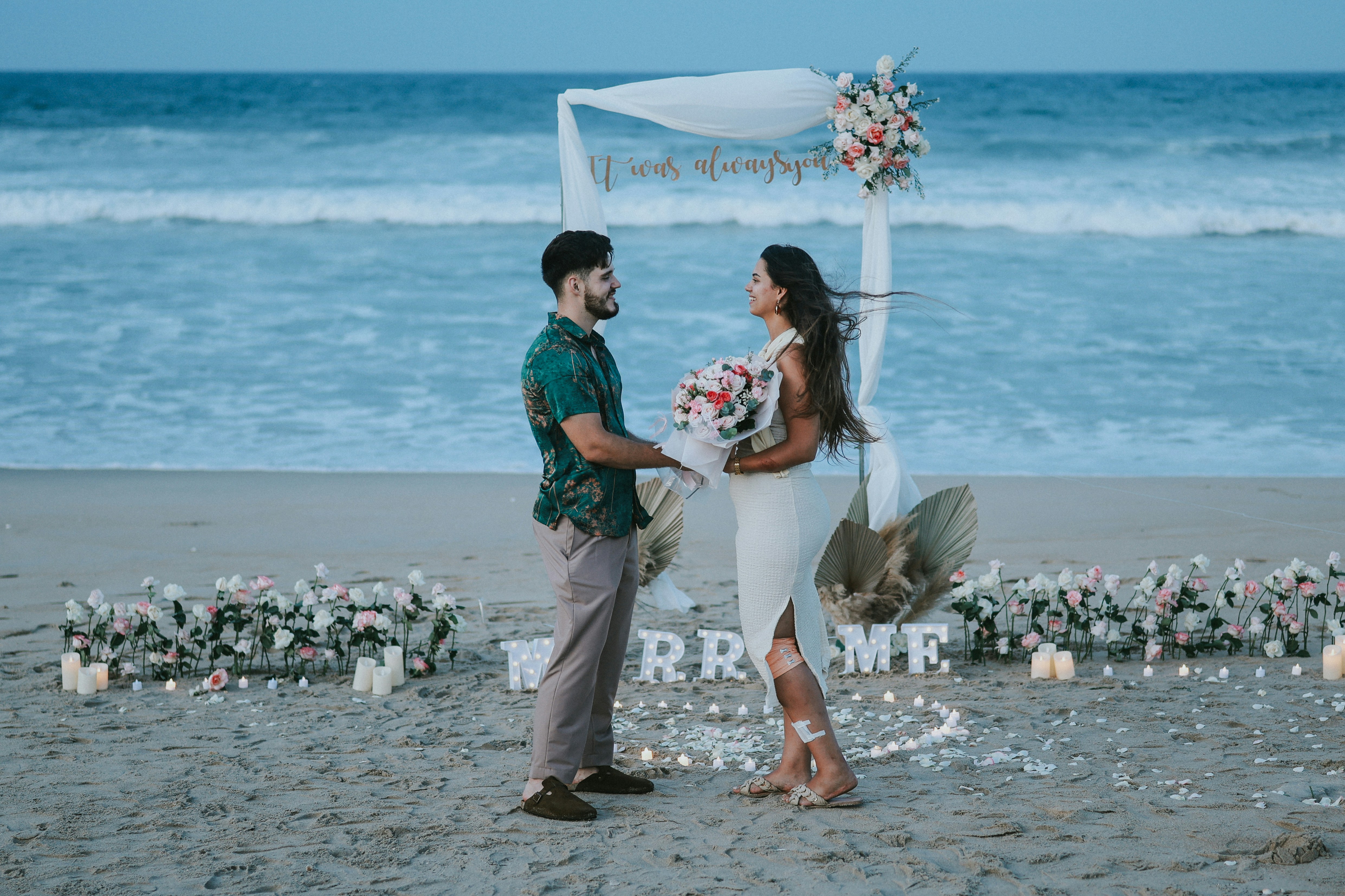 Couple on beach with "marry me" sign