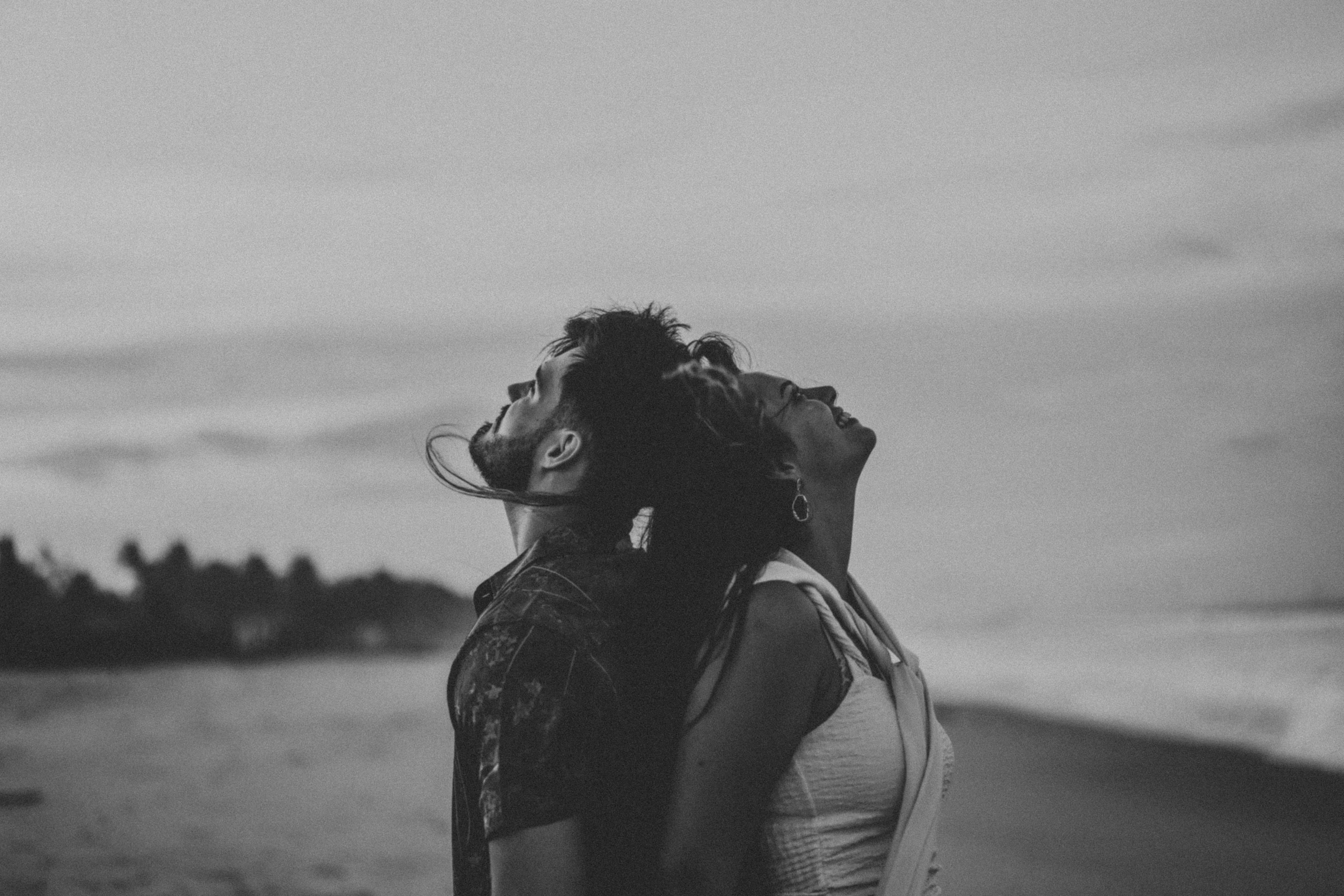 Couple leaning back to back on a beach.