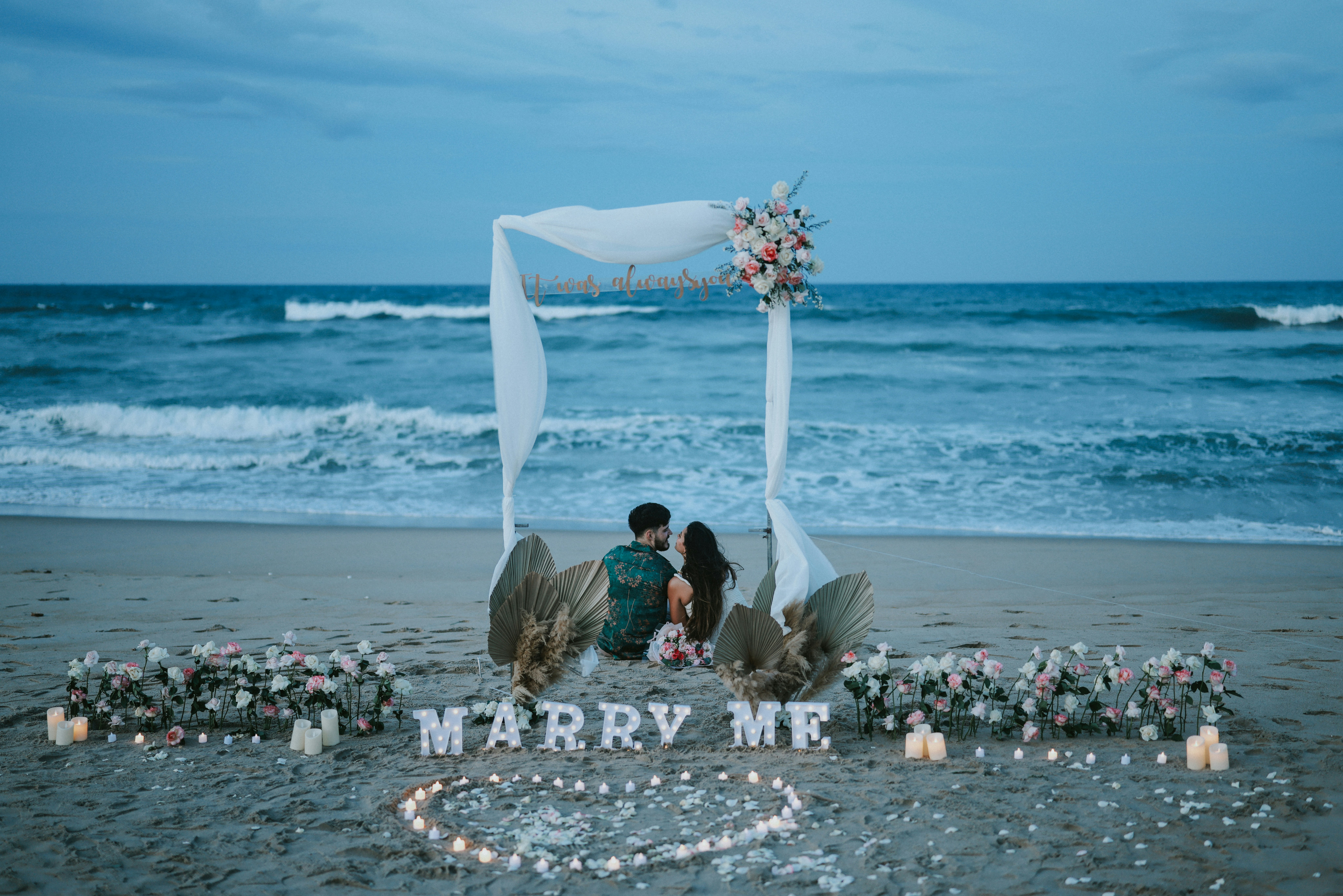 Couple on beach with 'marry me' proposal setup